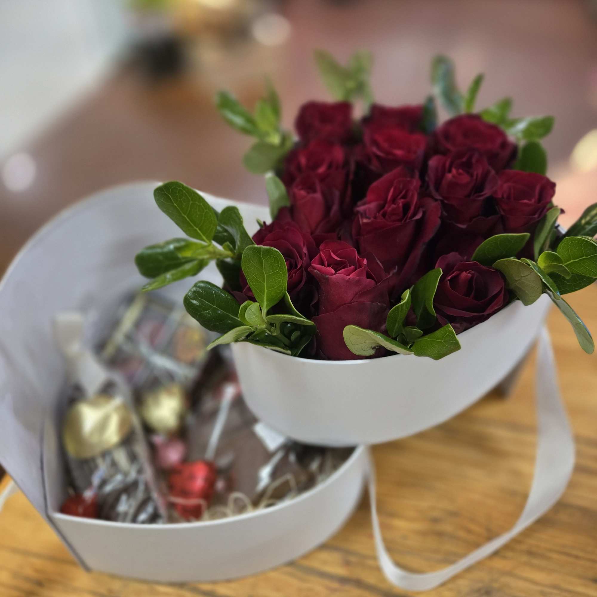 Bouquet of deep red roses with chocolates in white boxes