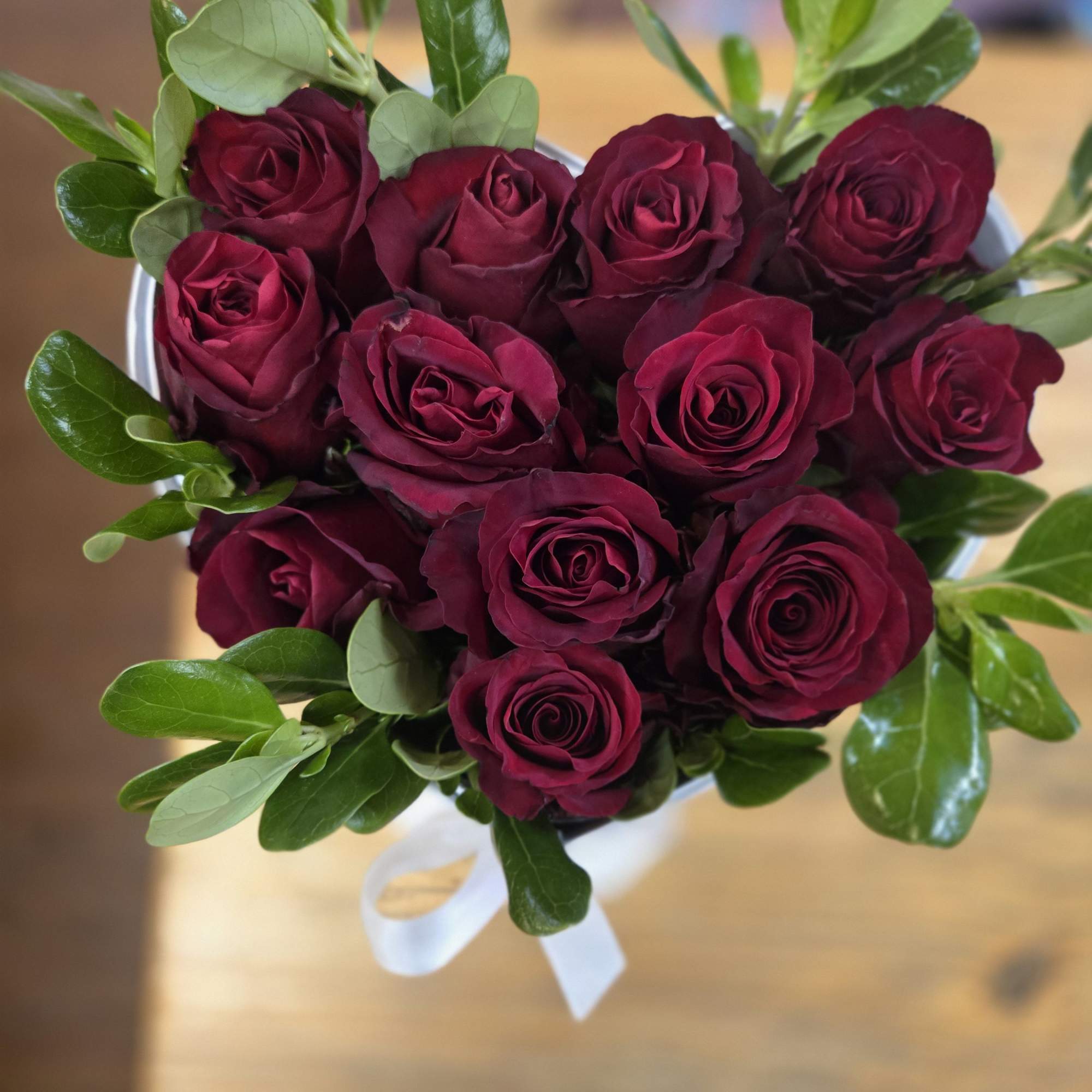 Bouquet of deep red roses with green foliage and a white ribbon
