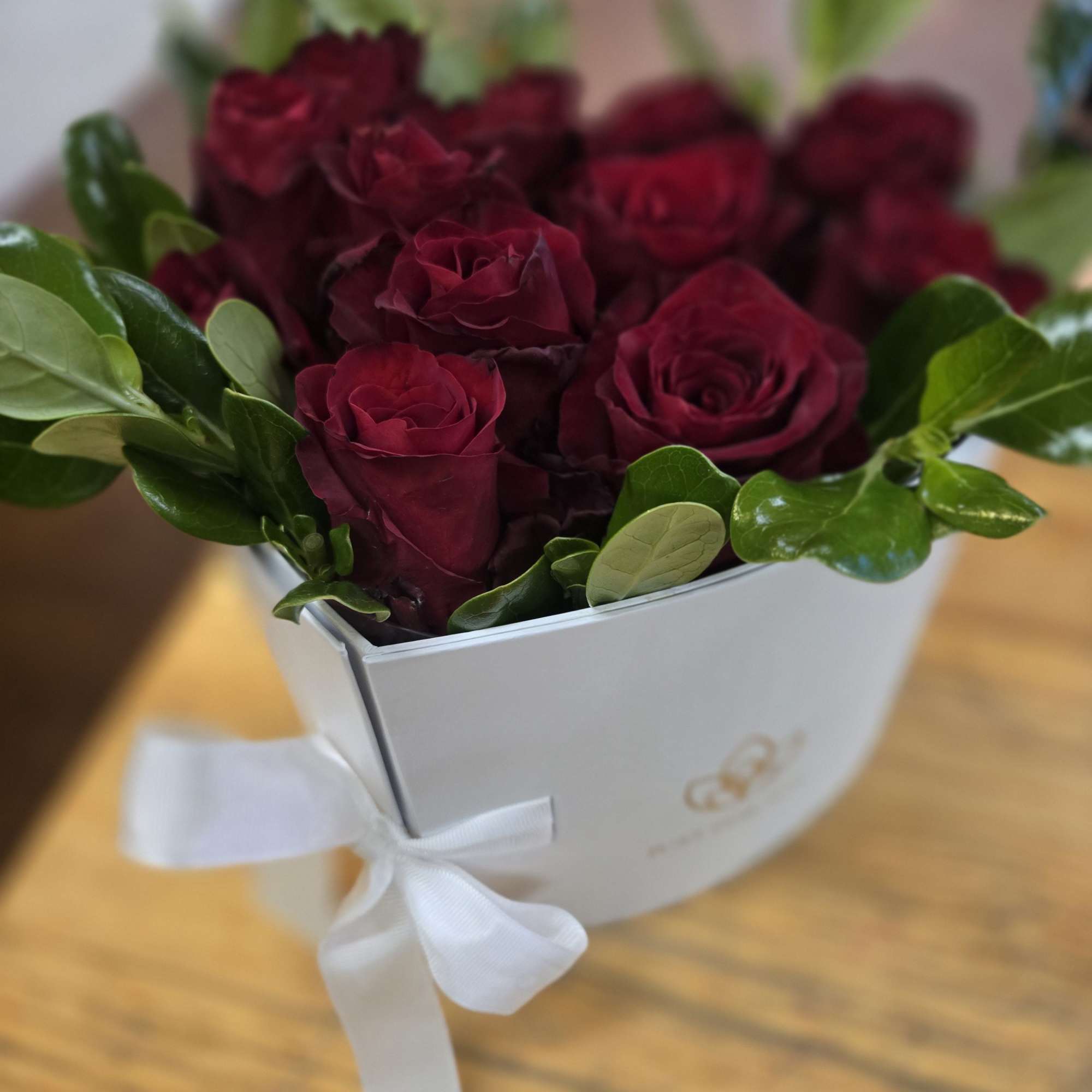 Bouquet of deep red roses in a white box tied with a ribbon