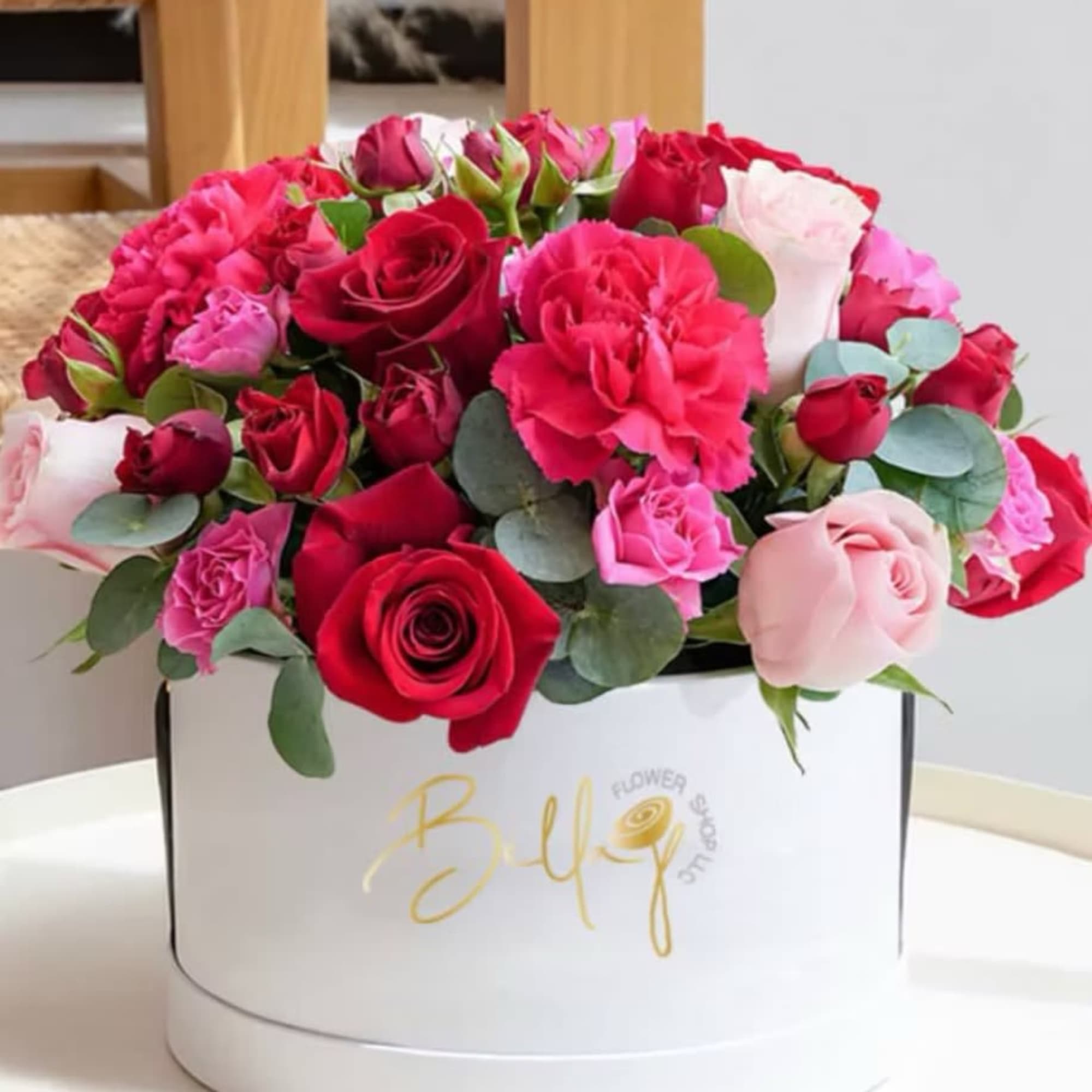 Pink and red roses with carnations in a white hat box