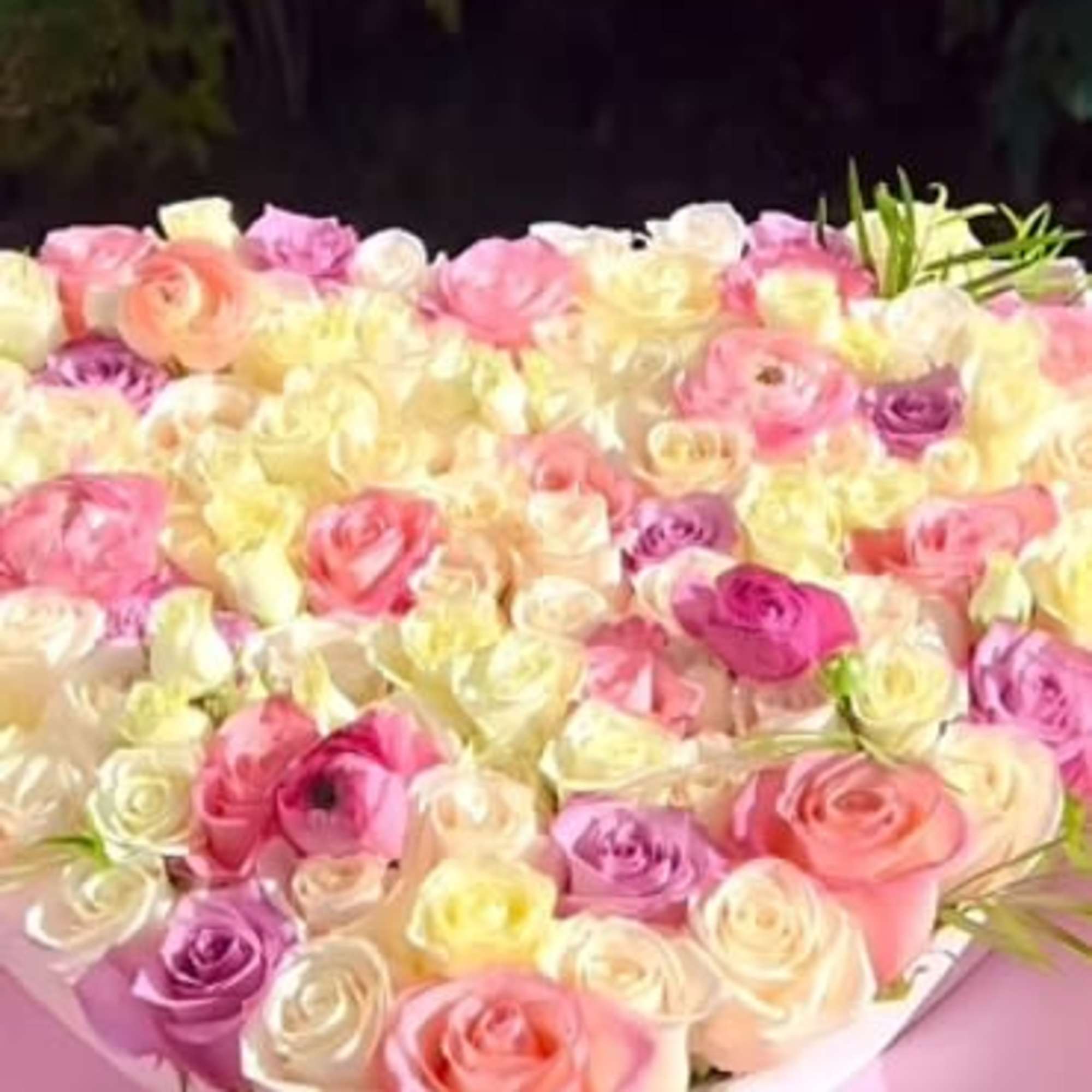 Large bouquet of pink, white, and lavender roses wrapped in pink paper