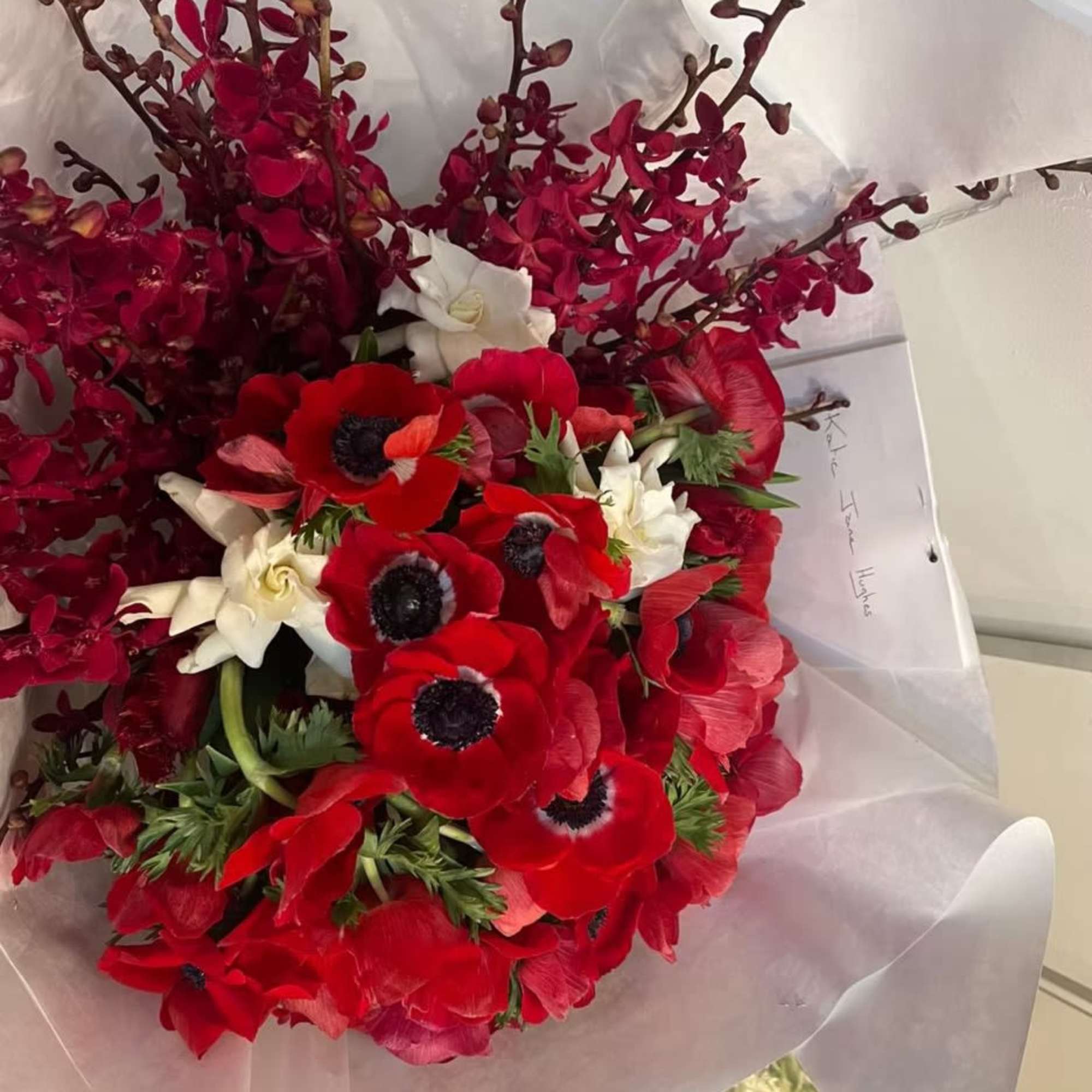 Bouquet of red anemones and white orchids wrapped in white paper