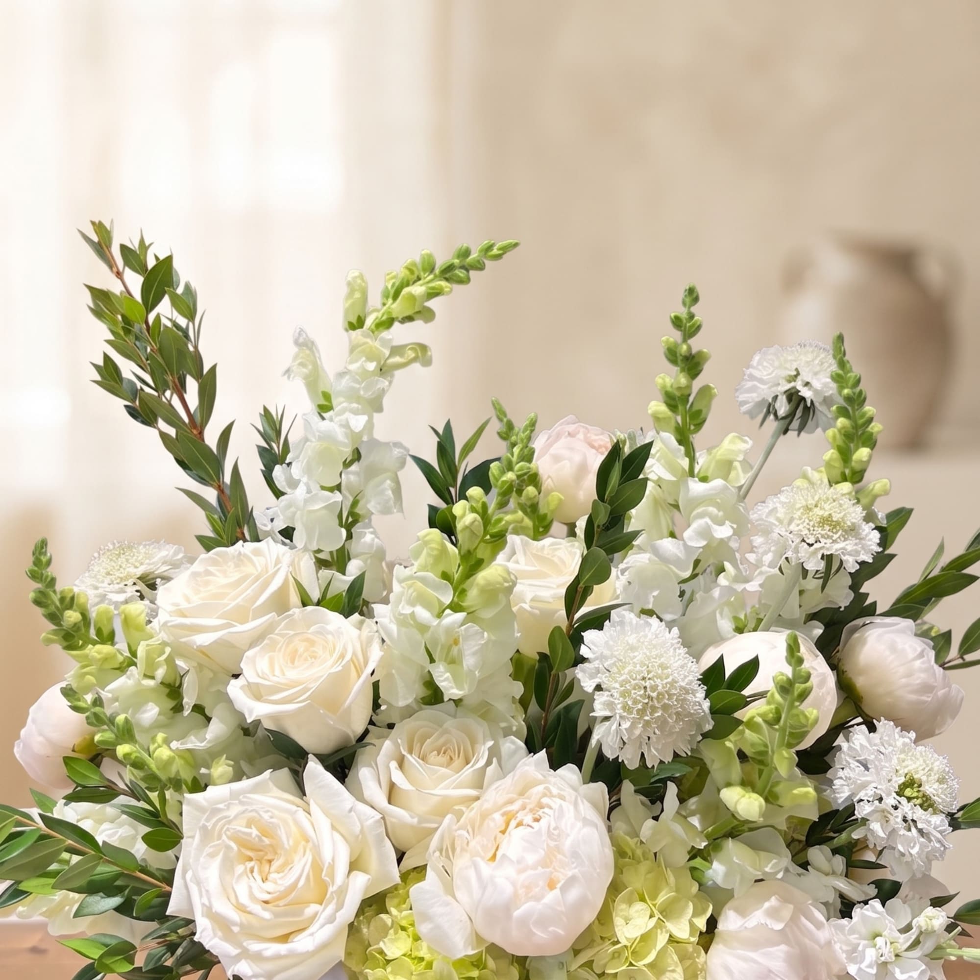 An elegant sympathy arrangement in a serene white and green palette. 

For