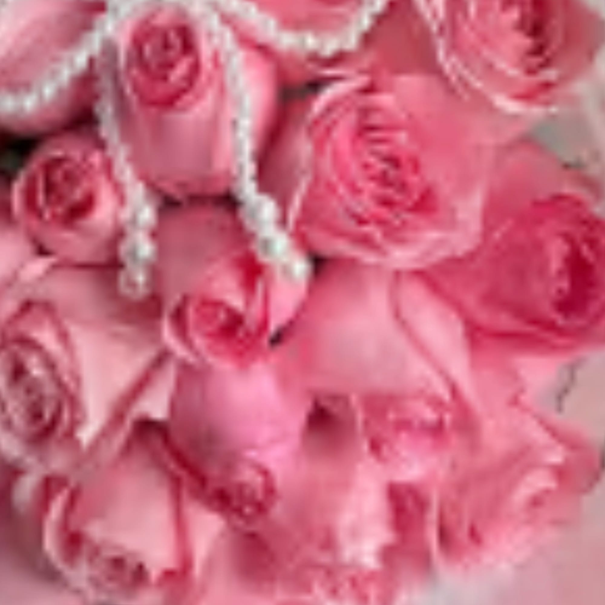 Pink roses with pearl strands draped over the bouquet