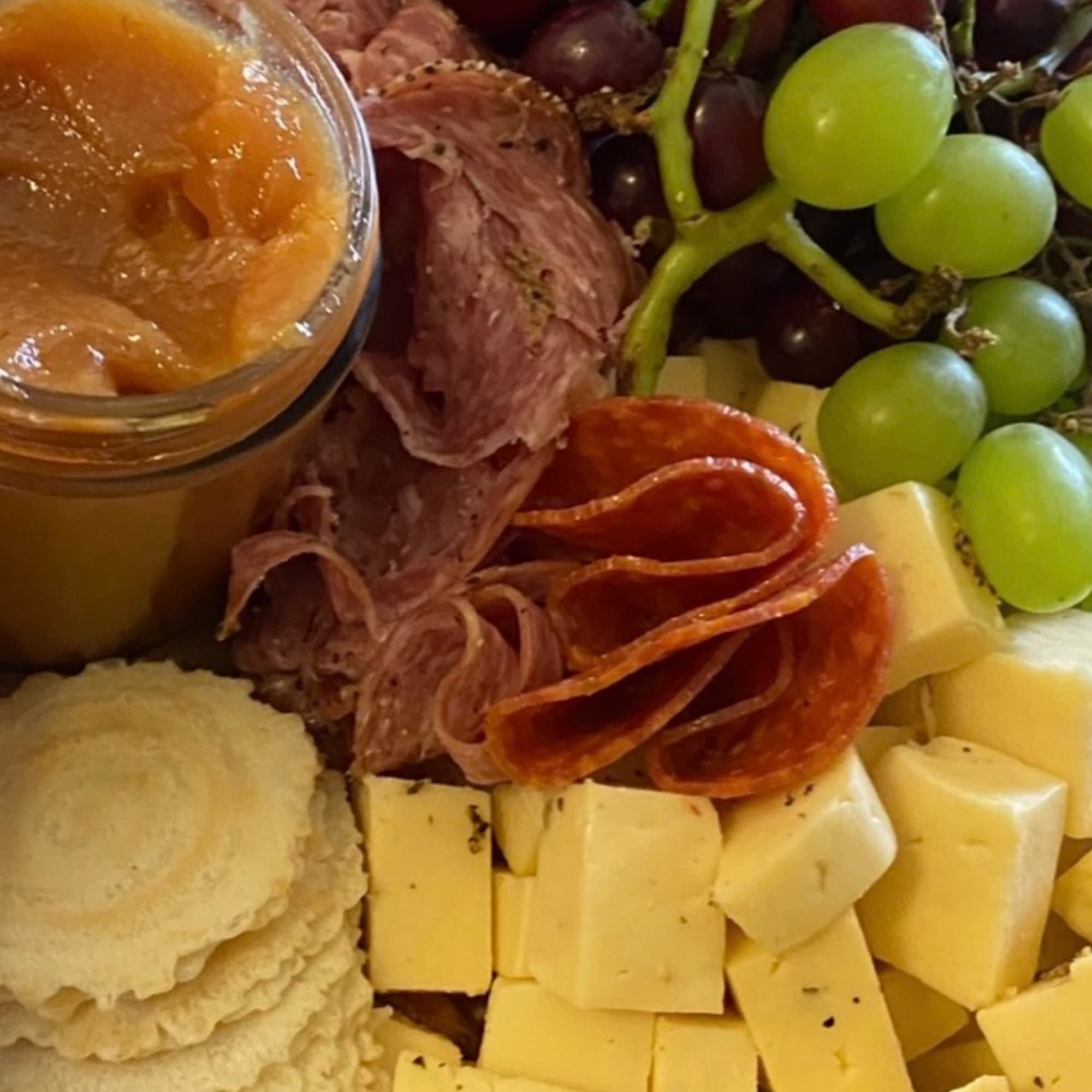 Charcuterie board with grapes, cheese cubes, crackers, and sliced meat