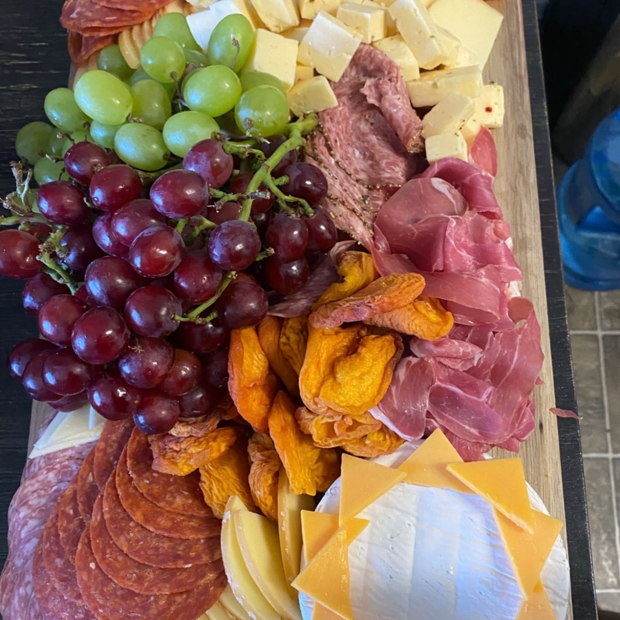 Charcuterie board with grapes, cheeses, cured meats, and dried fruit, photo 4 of 7