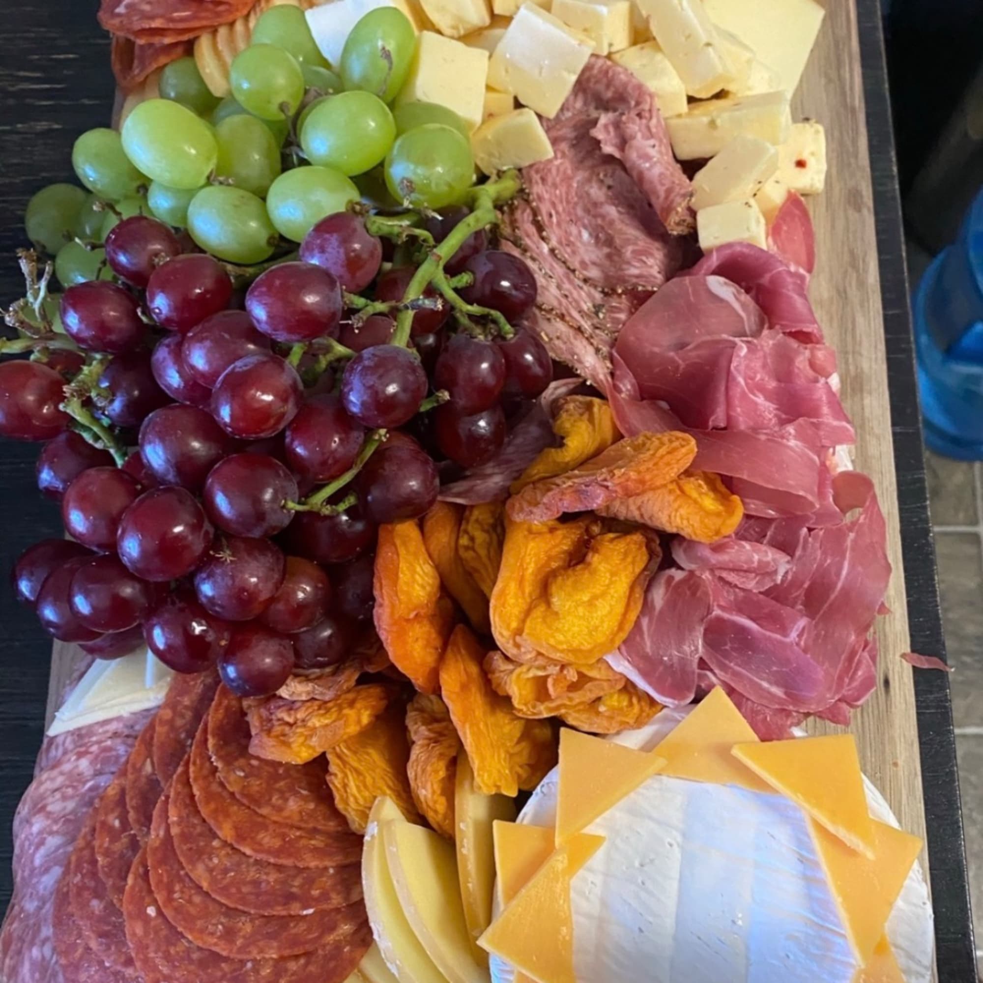 Charcuterie board with grapes, cheeses, cured meats, and dried fruit, photo 2 of 7