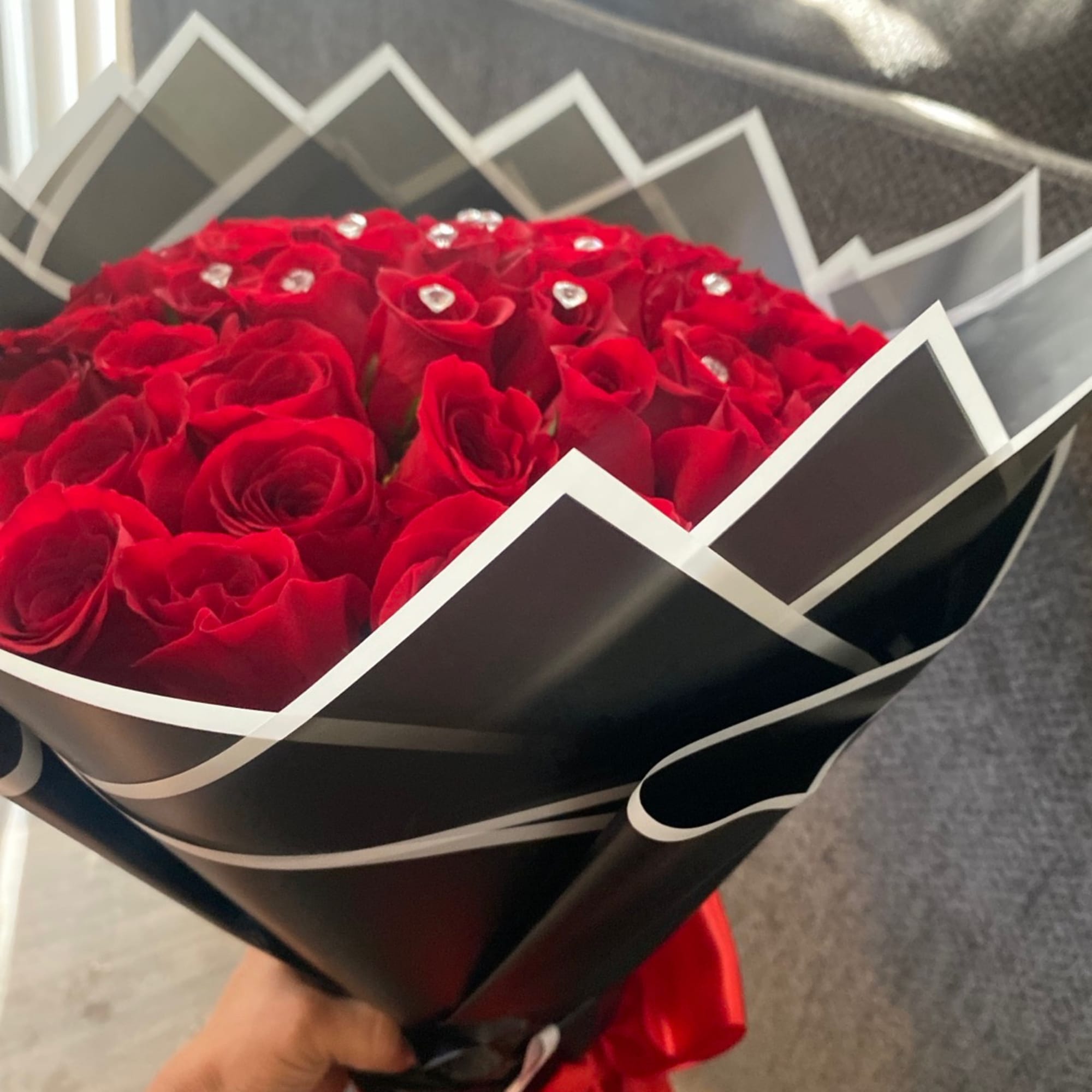 Bouquet of red roses wrapped in black paper with white trim