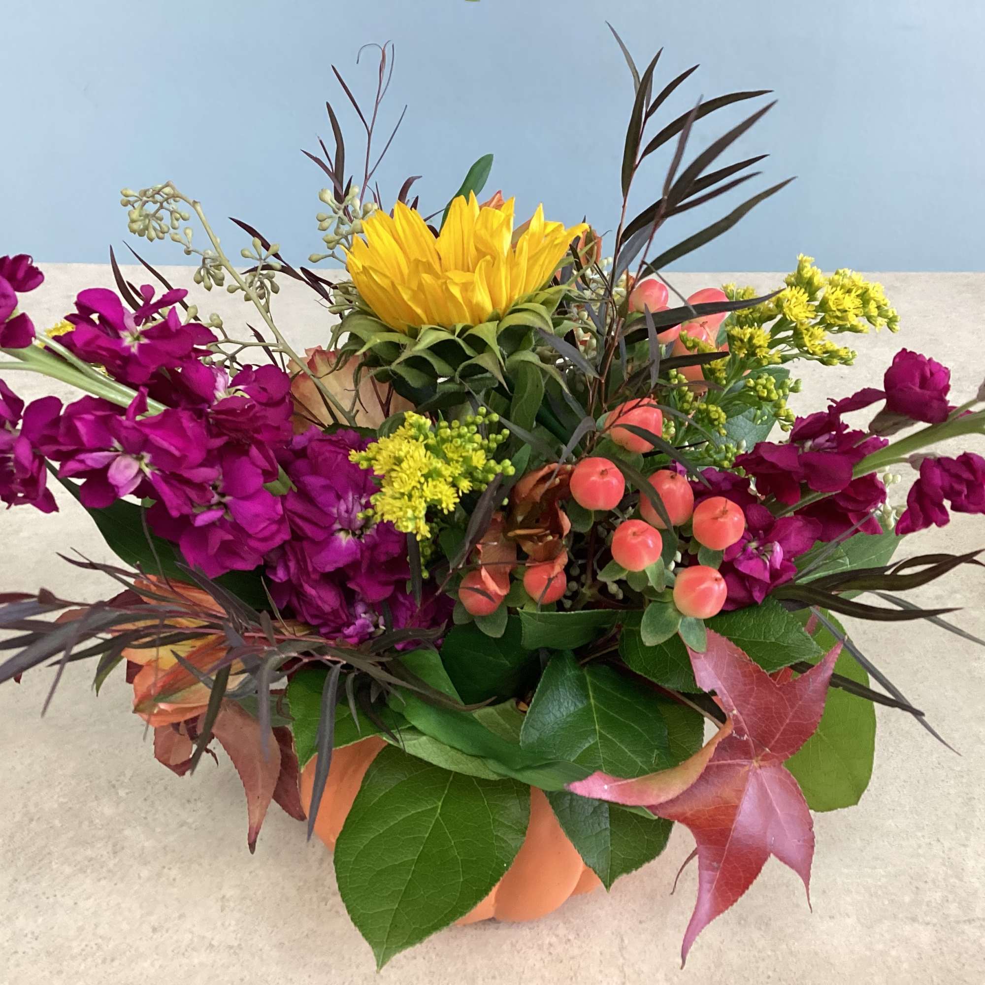 Colorful mixed flower arrangement with yellow and magenta blooms in a low container