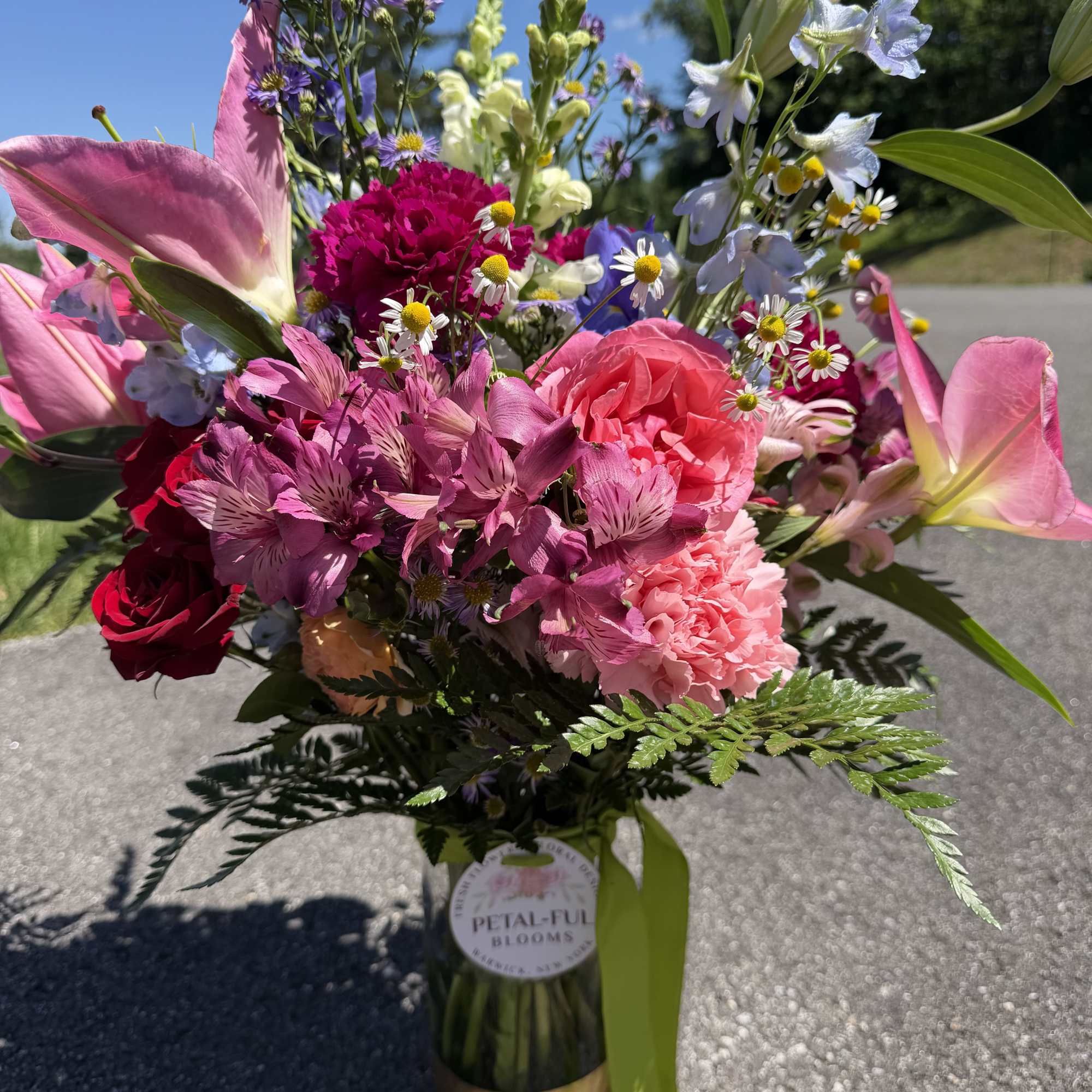 This arrangement contains stargazer lilies, bells of ireland, stock, blue iris, roses