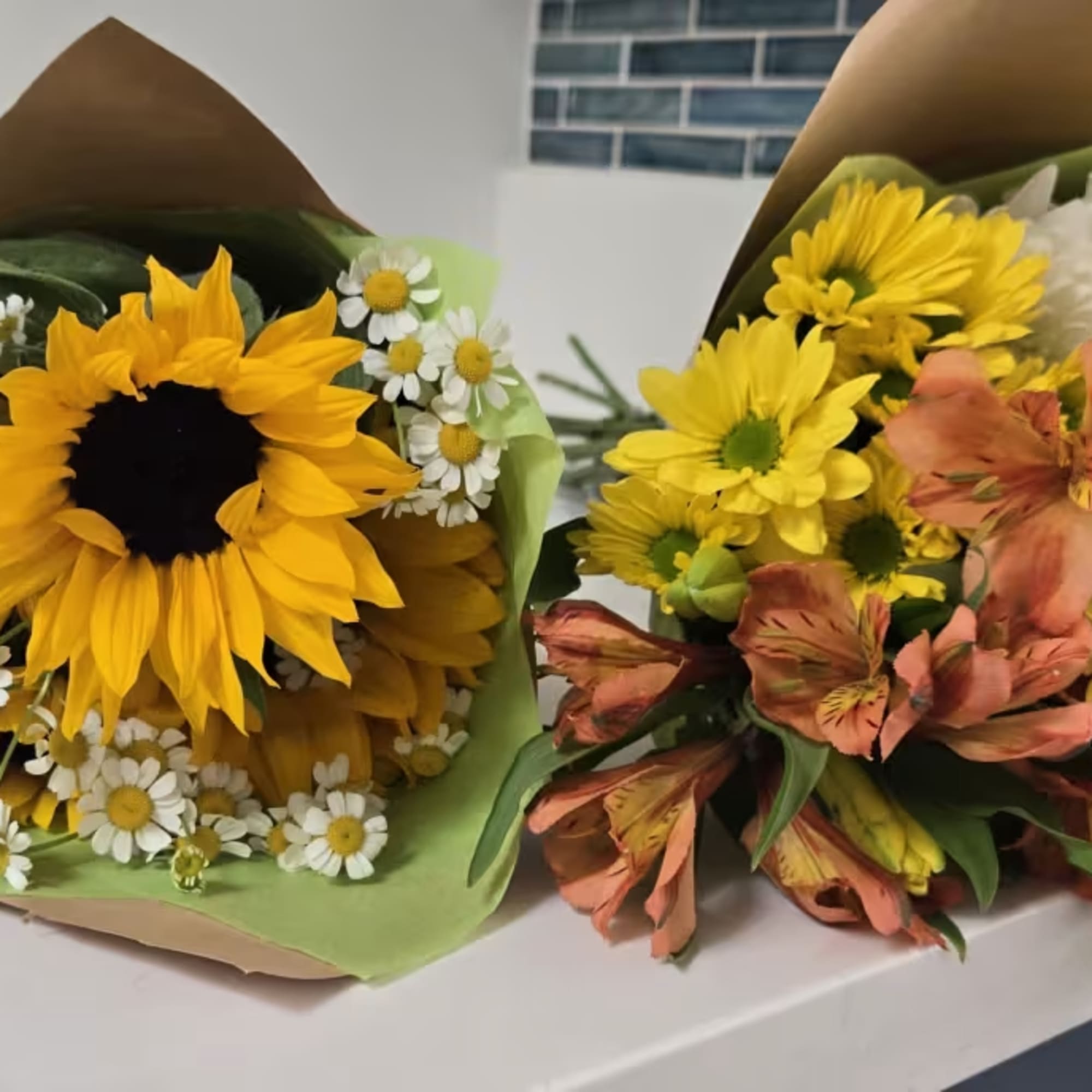 Two wrapped bouquets with sunflowers, daisies, and yellow blooms