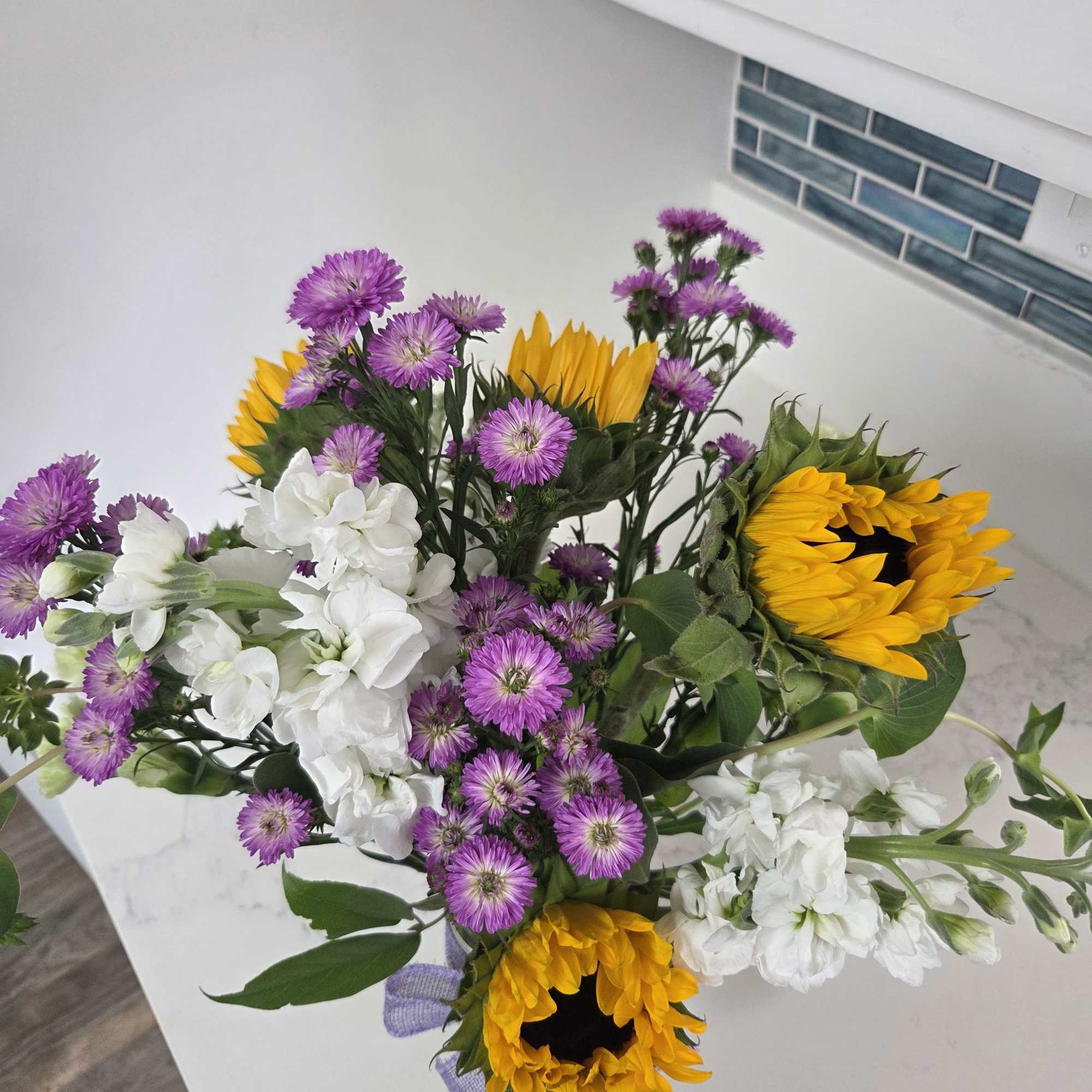 Bouquet of sunflowers, white stock, and purple asters
