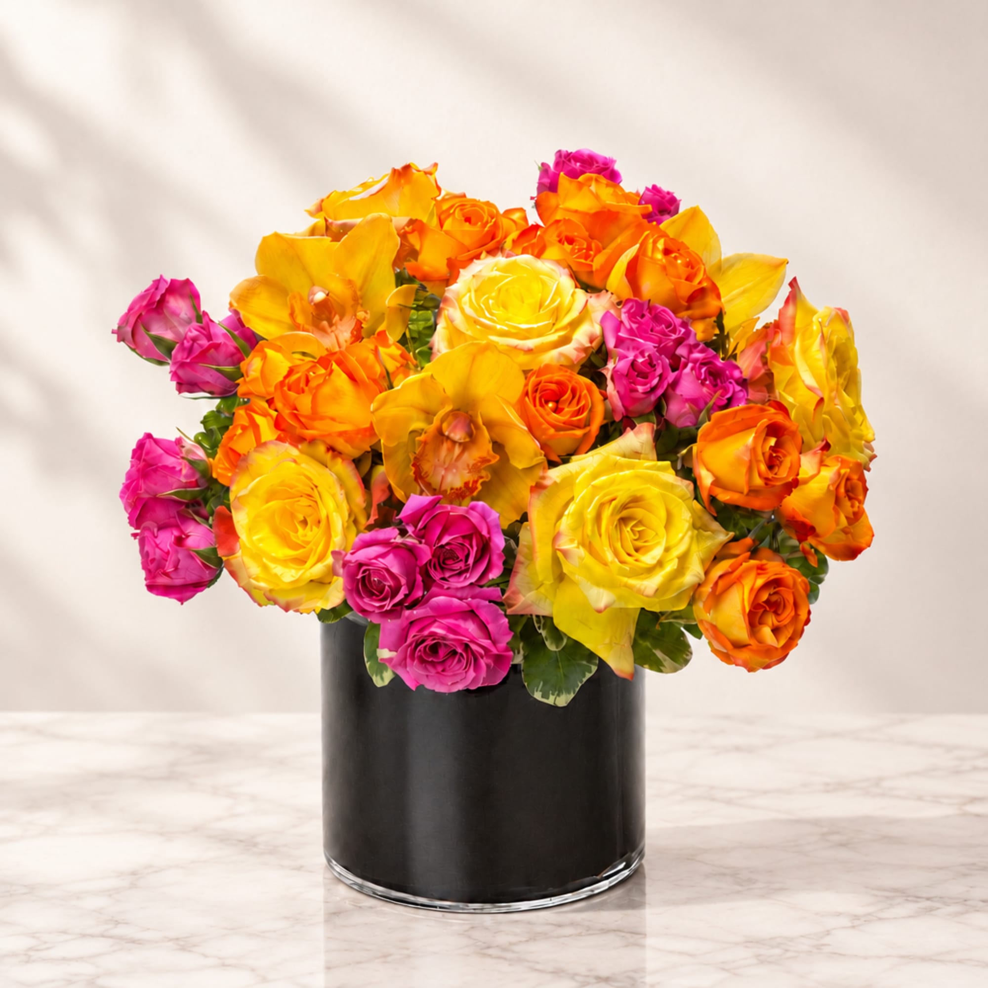 Bouquet of yellow, orange, and pink roses in a black vase