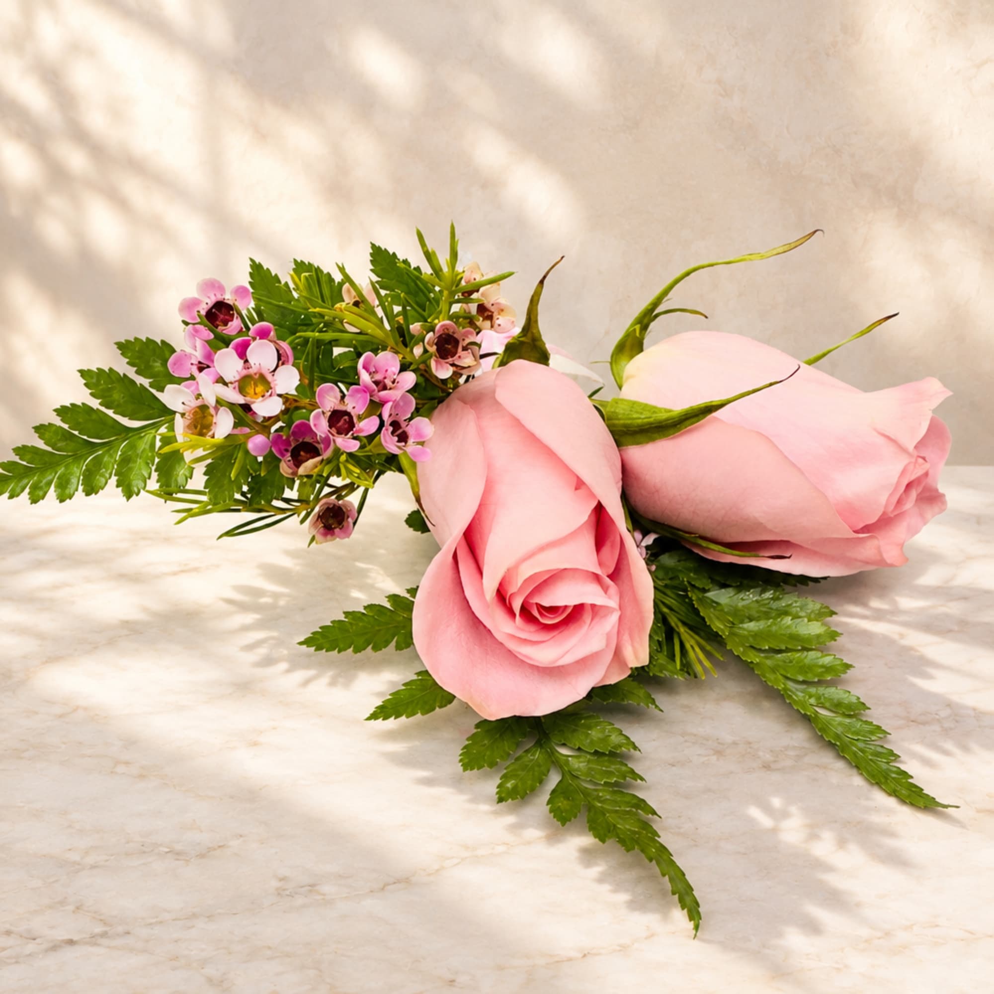 Two pink roses with small pink filler flowers and greenery
