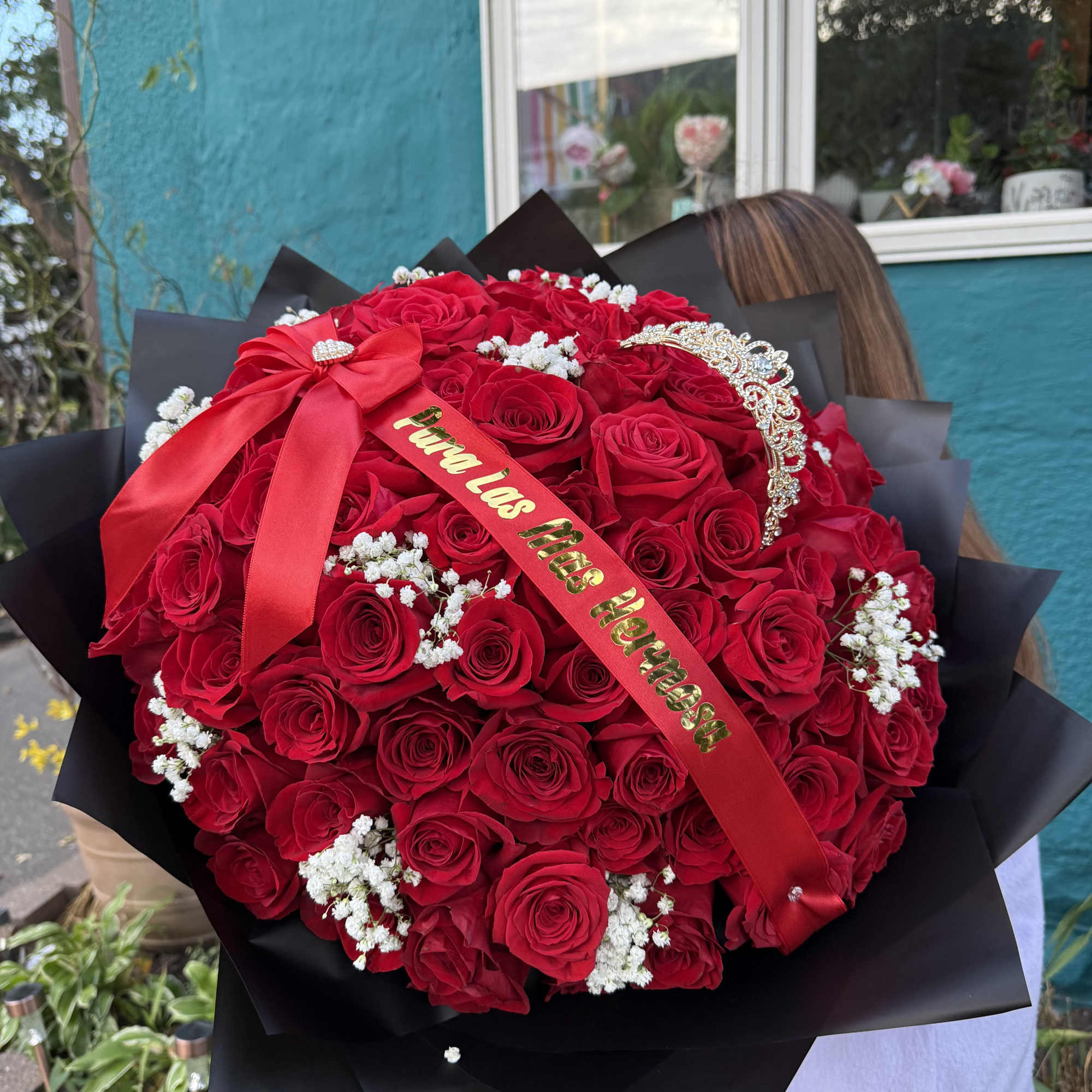 Large bouquet of red roses with a red ribbon and jeweled tiara
