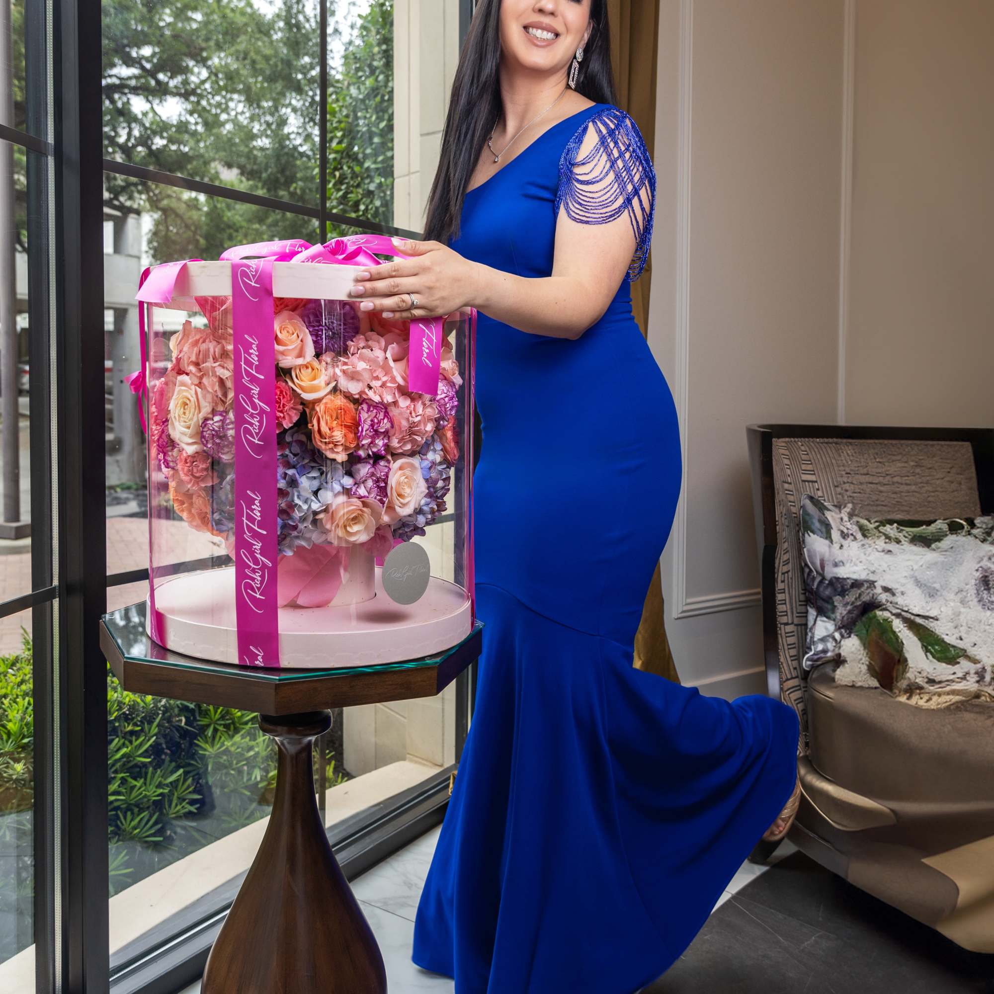 Woman in blue dress holding a boxed pastel rose arrangement