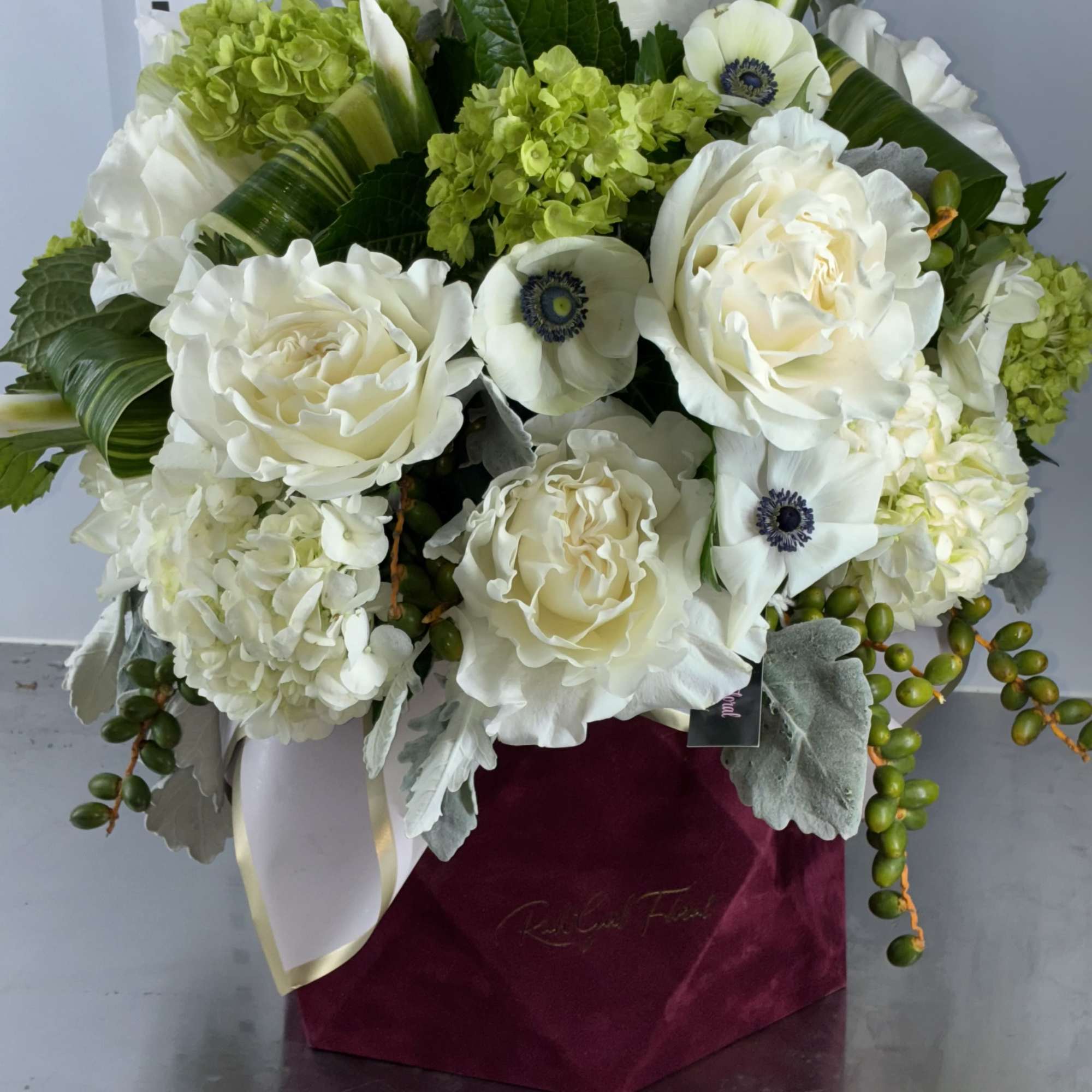 White roses and green hydrangeas in a burgundy box