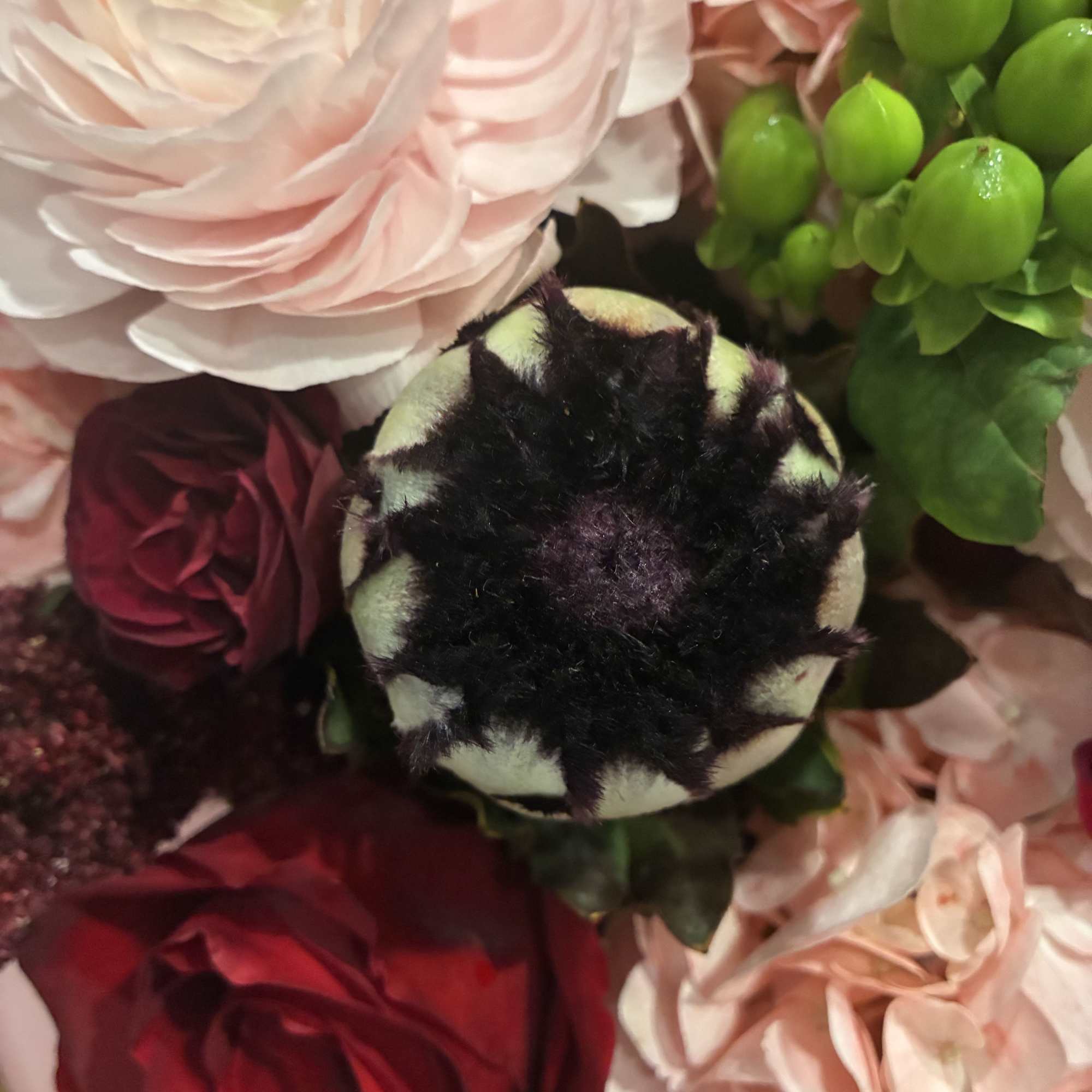 Close-up bouquet of pale pink and red flowers with a dark center bloom