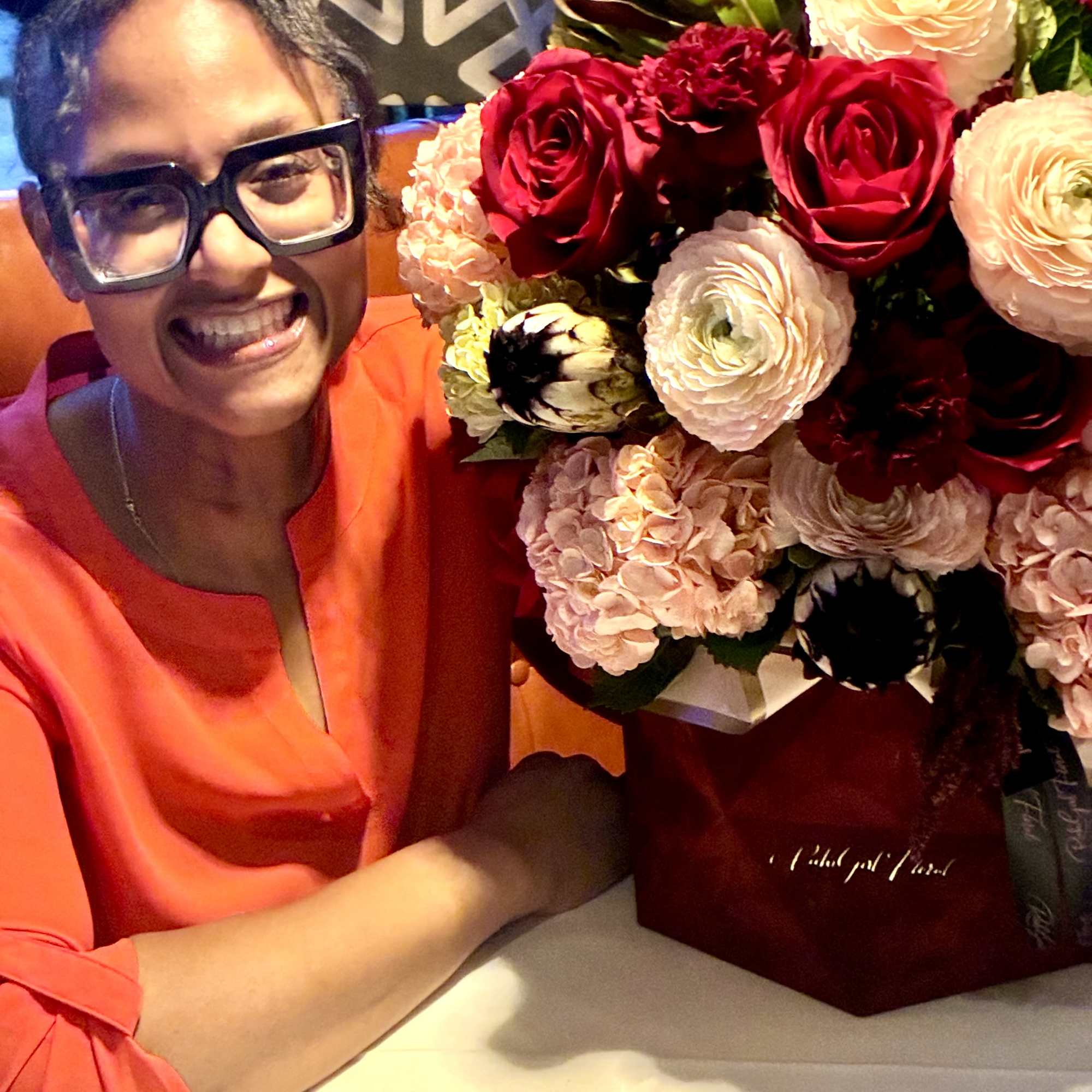 Woman smiling beside a bouquet of red and blush flowers in a box