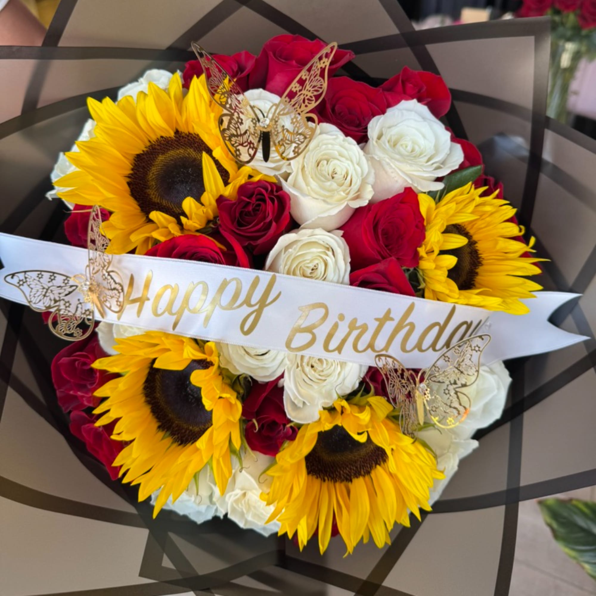 Bouquet of red and white roses with sunflowers and a birthday ribbon