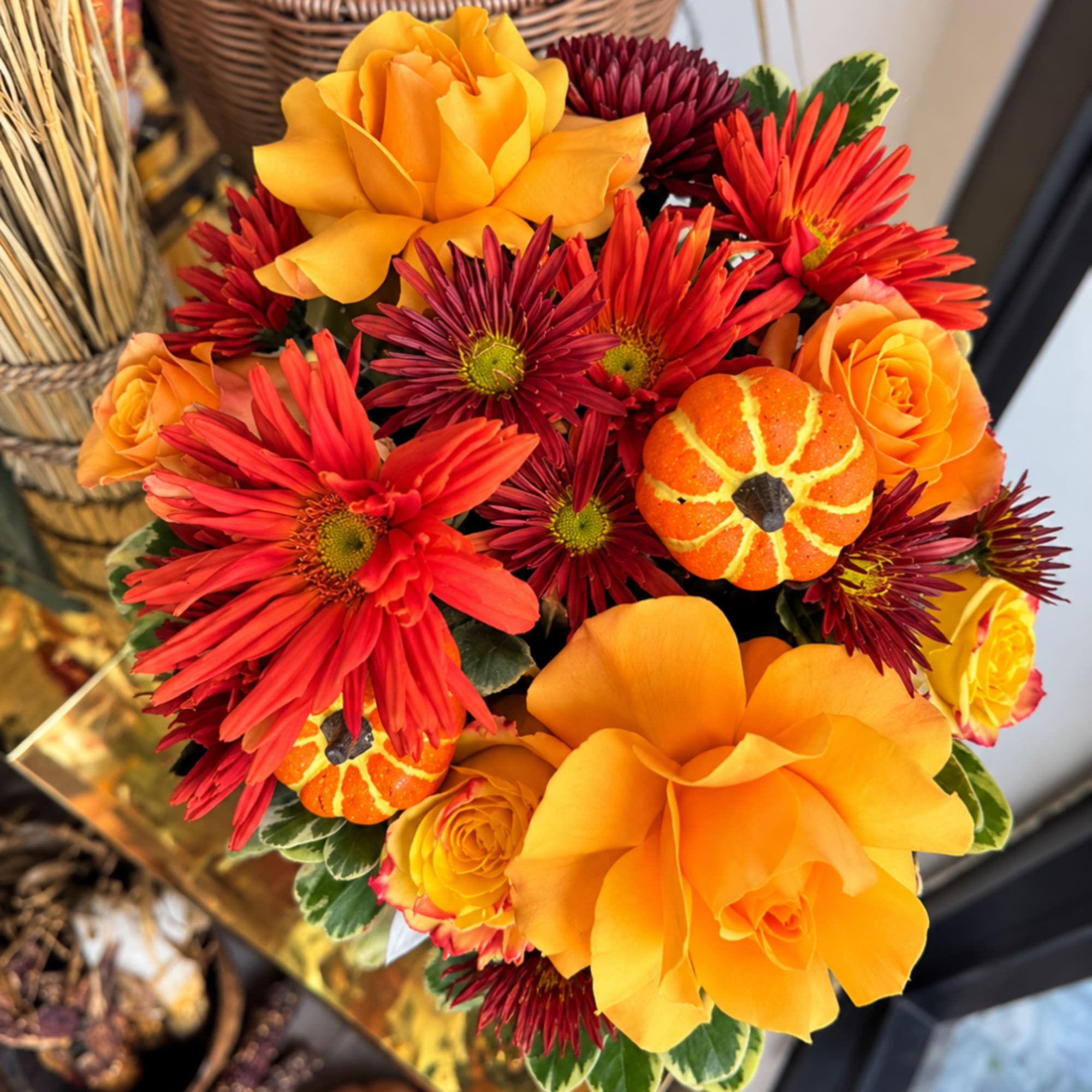 Bouquet of orange roses and red chrysanthemums with small pumpkin accents