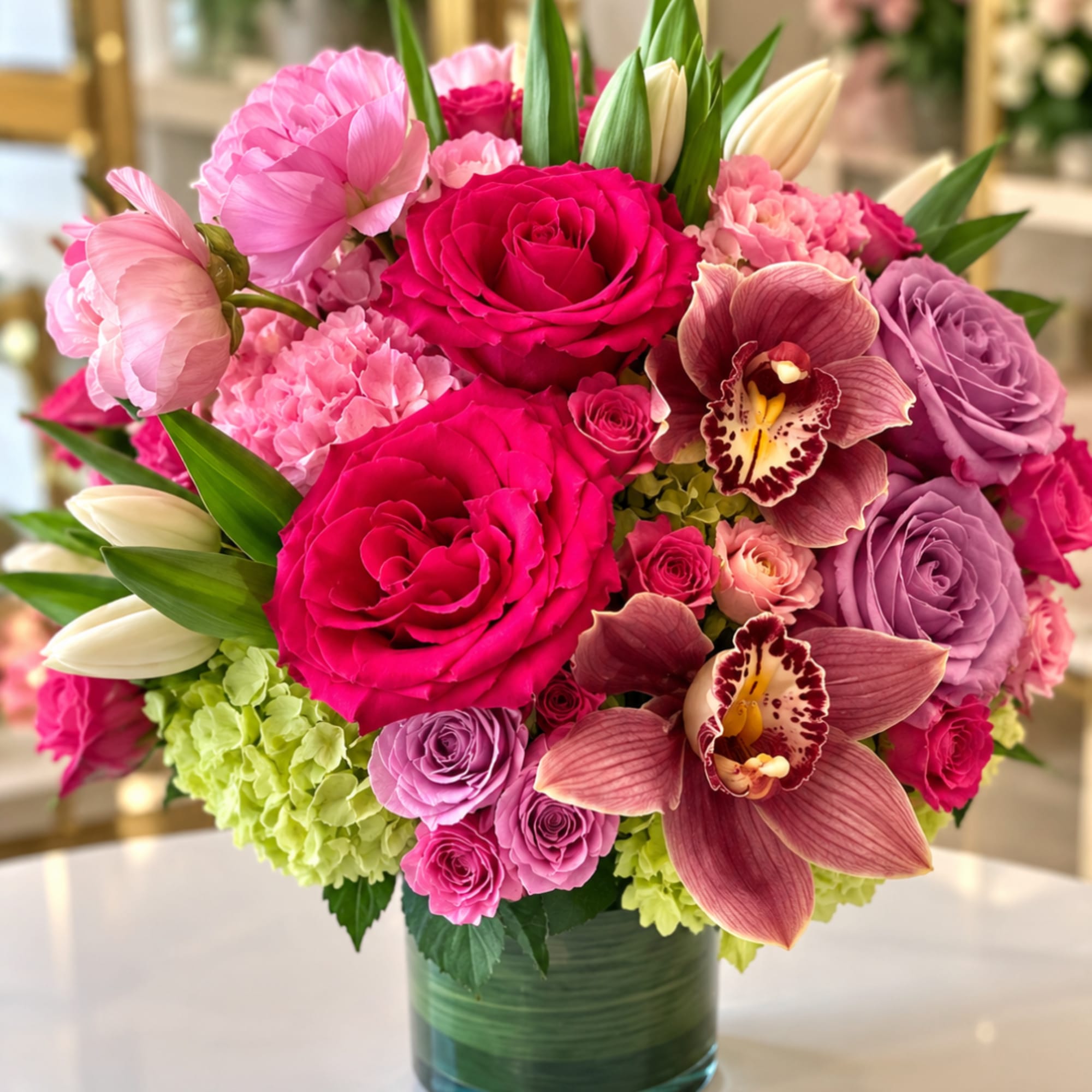 Pink and lavender bouquet with roses, orchids, and lilies in a glass vase
