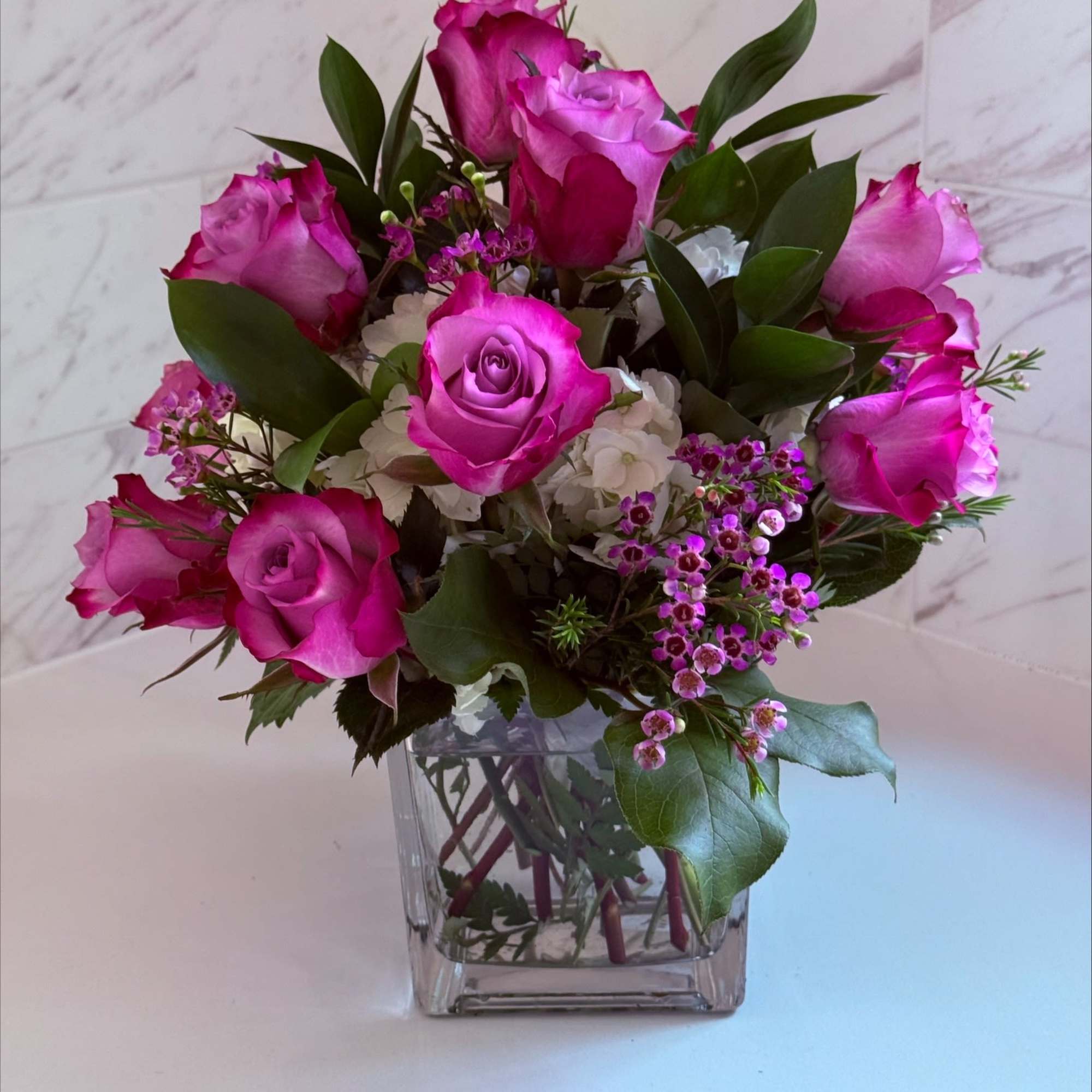 Pink roses arranged in a clear square glass vase