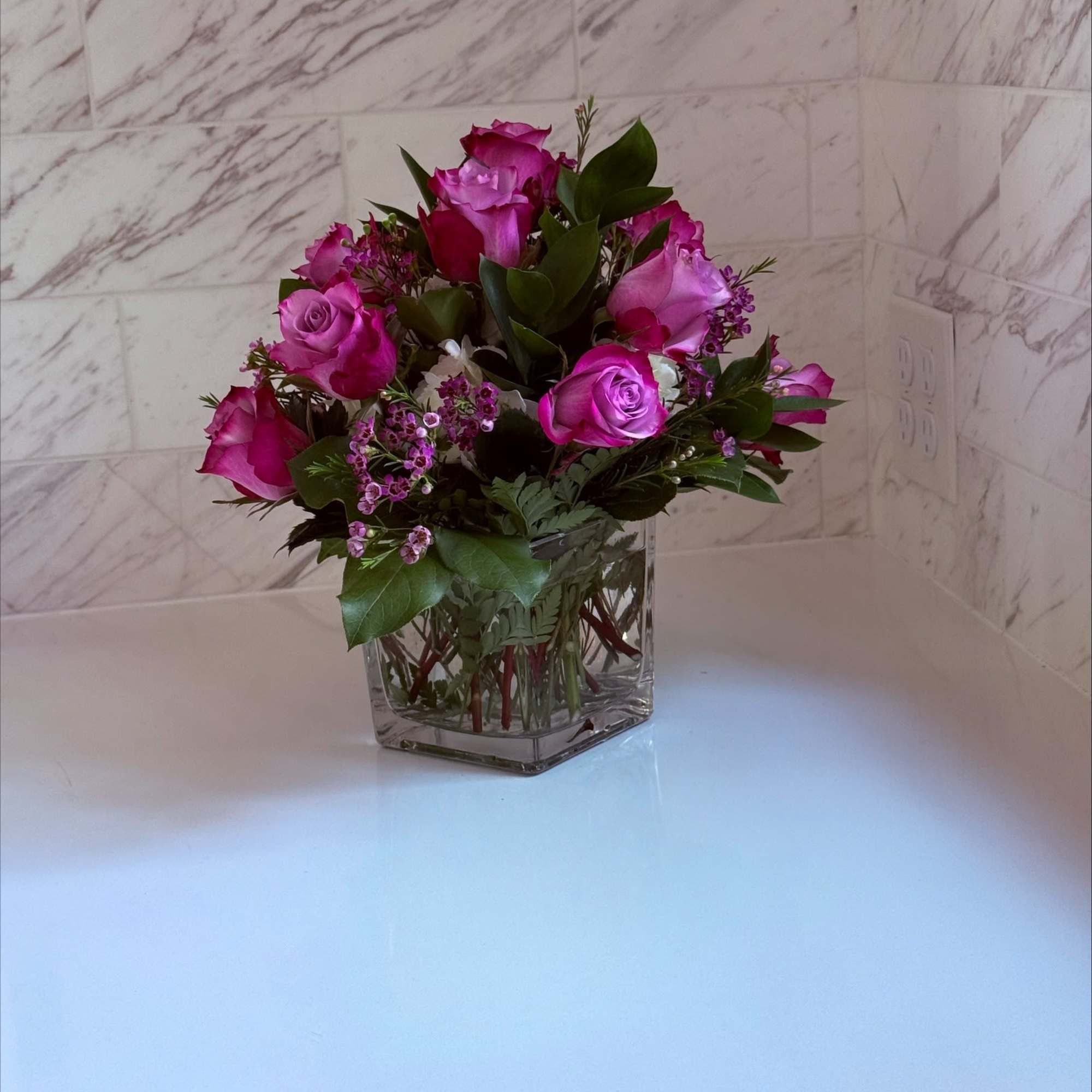 Pink roses arranged in a clear square vase