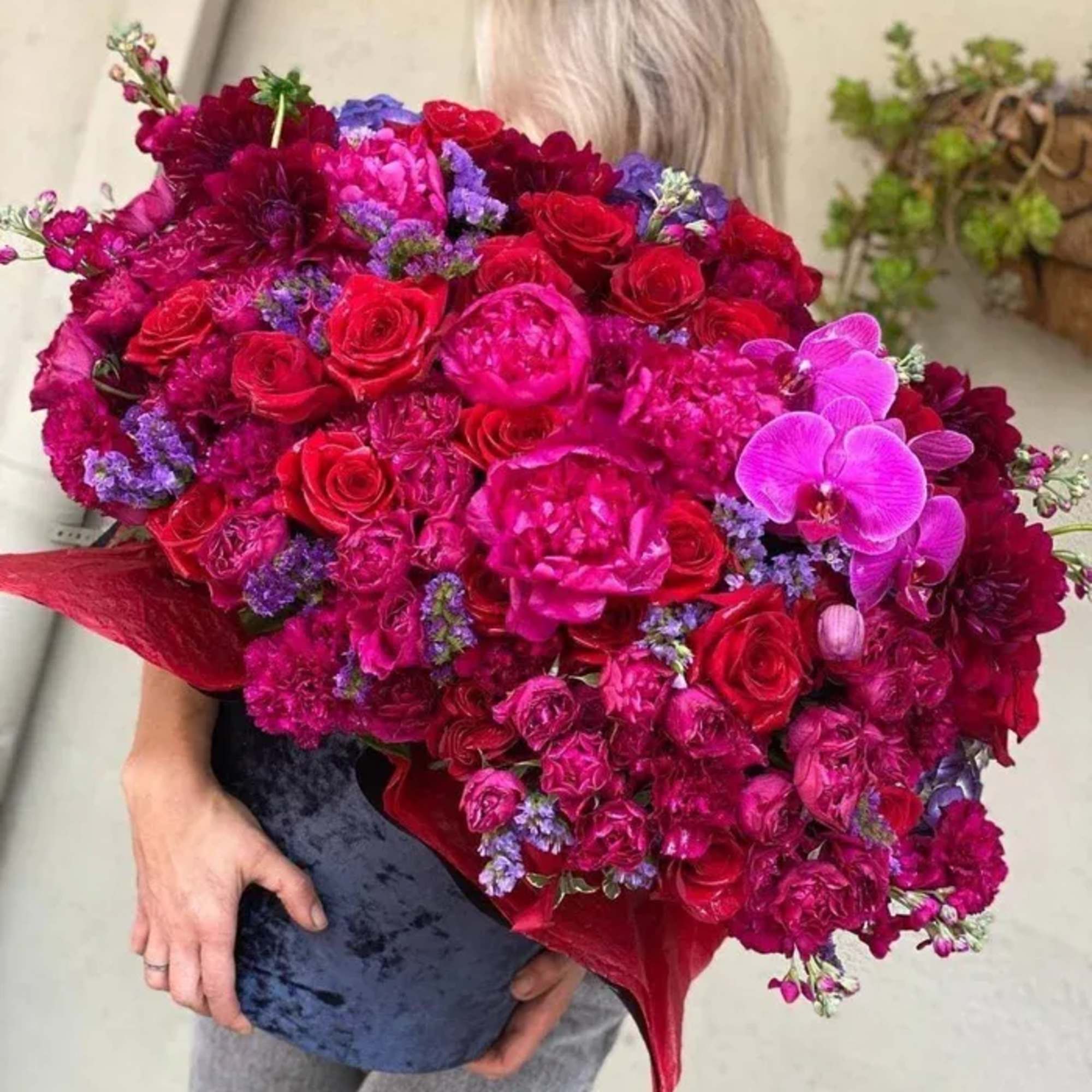 Large bouquet of red, pink, and purple flowers held by a person