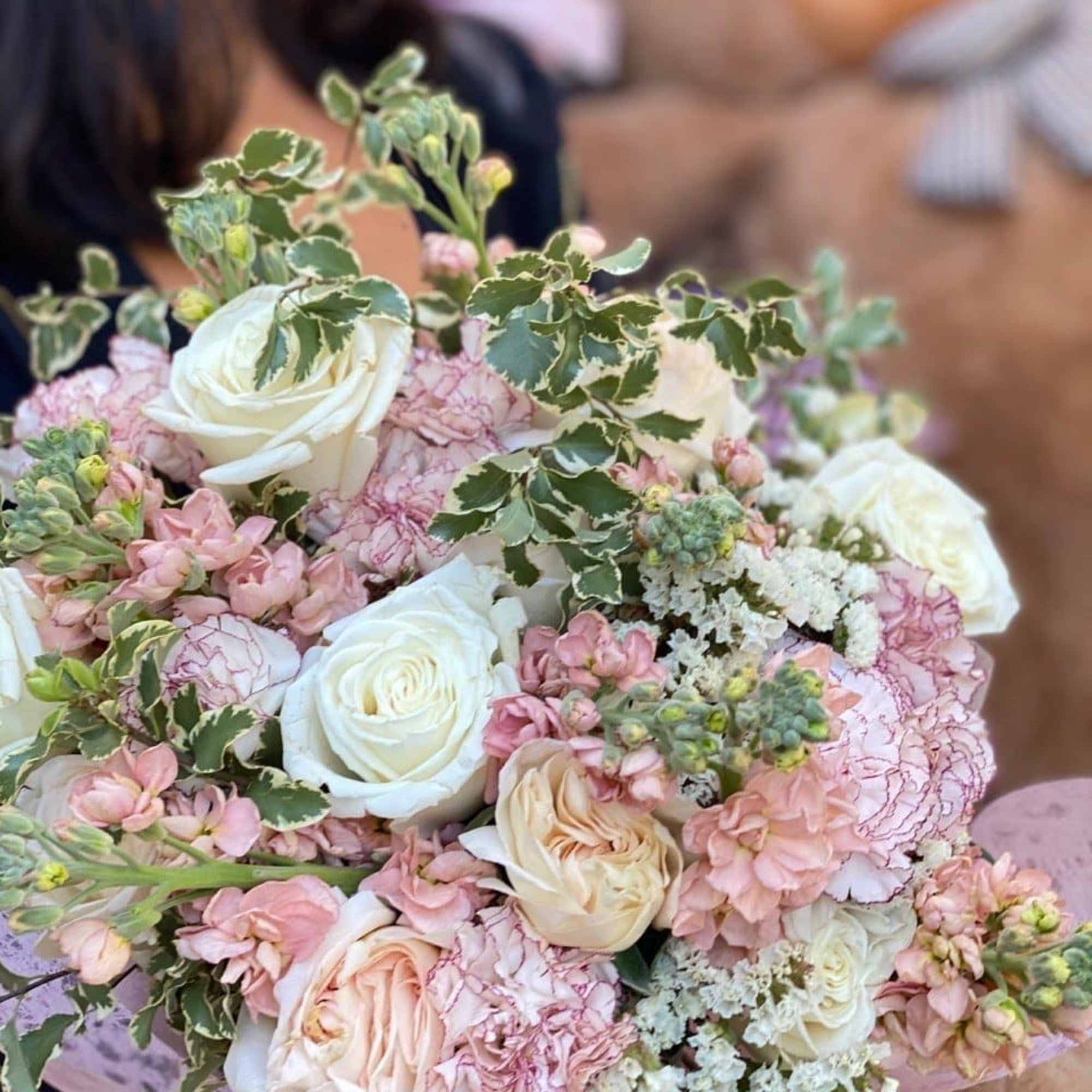 Bouquet of white and blush roses with pink carnations and variegated greenery