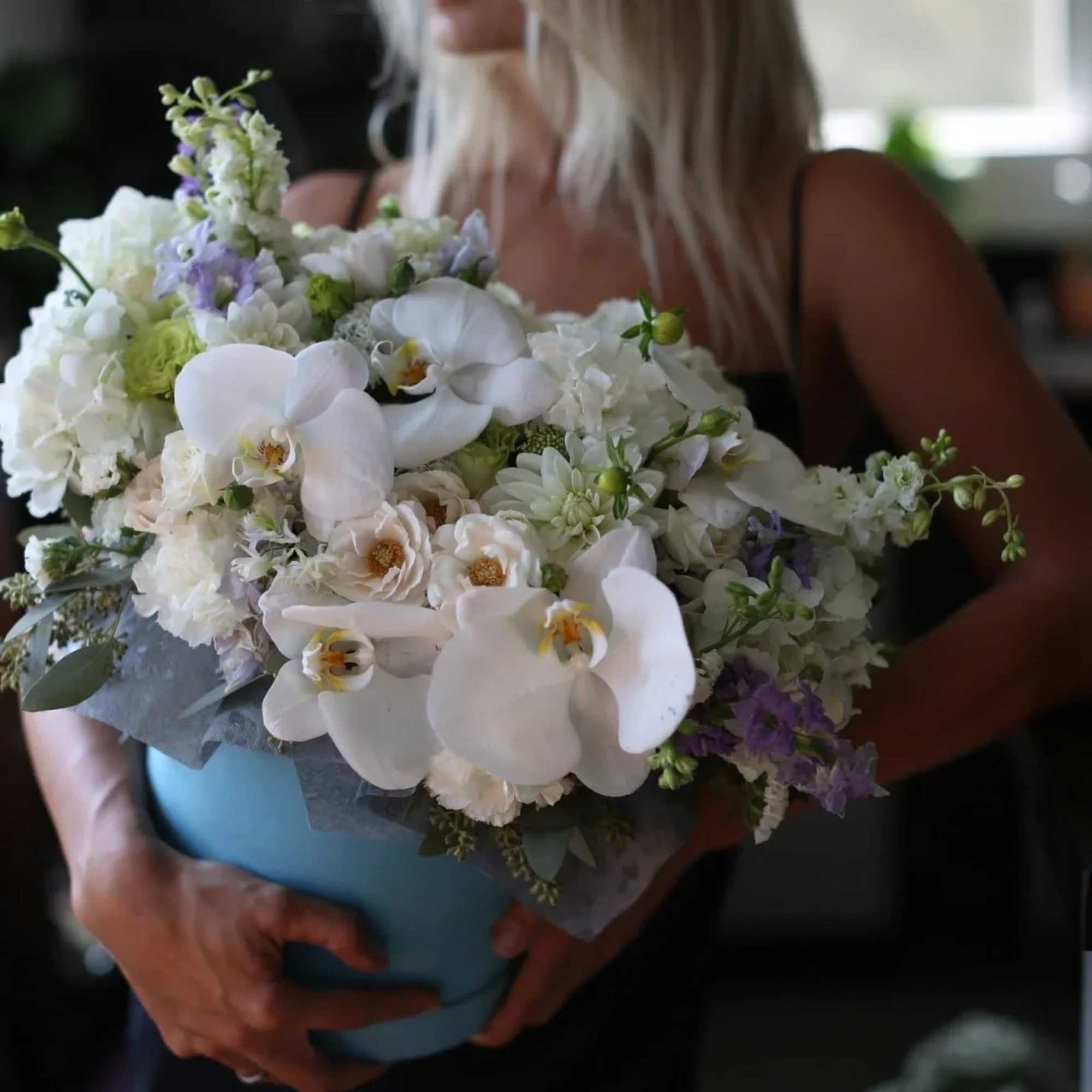 Woman holding a large bouquet of white and lavender flowers