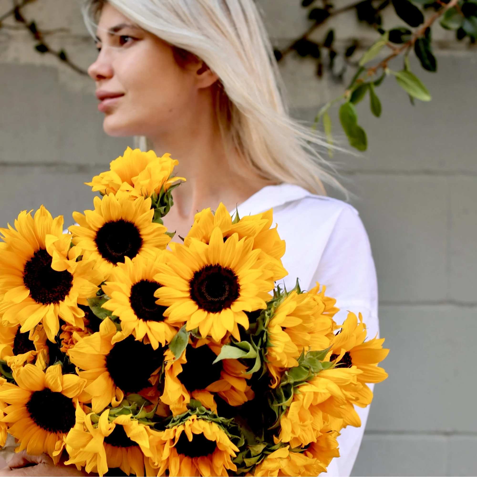Woman holding a large bouquet of yellow sunflowers