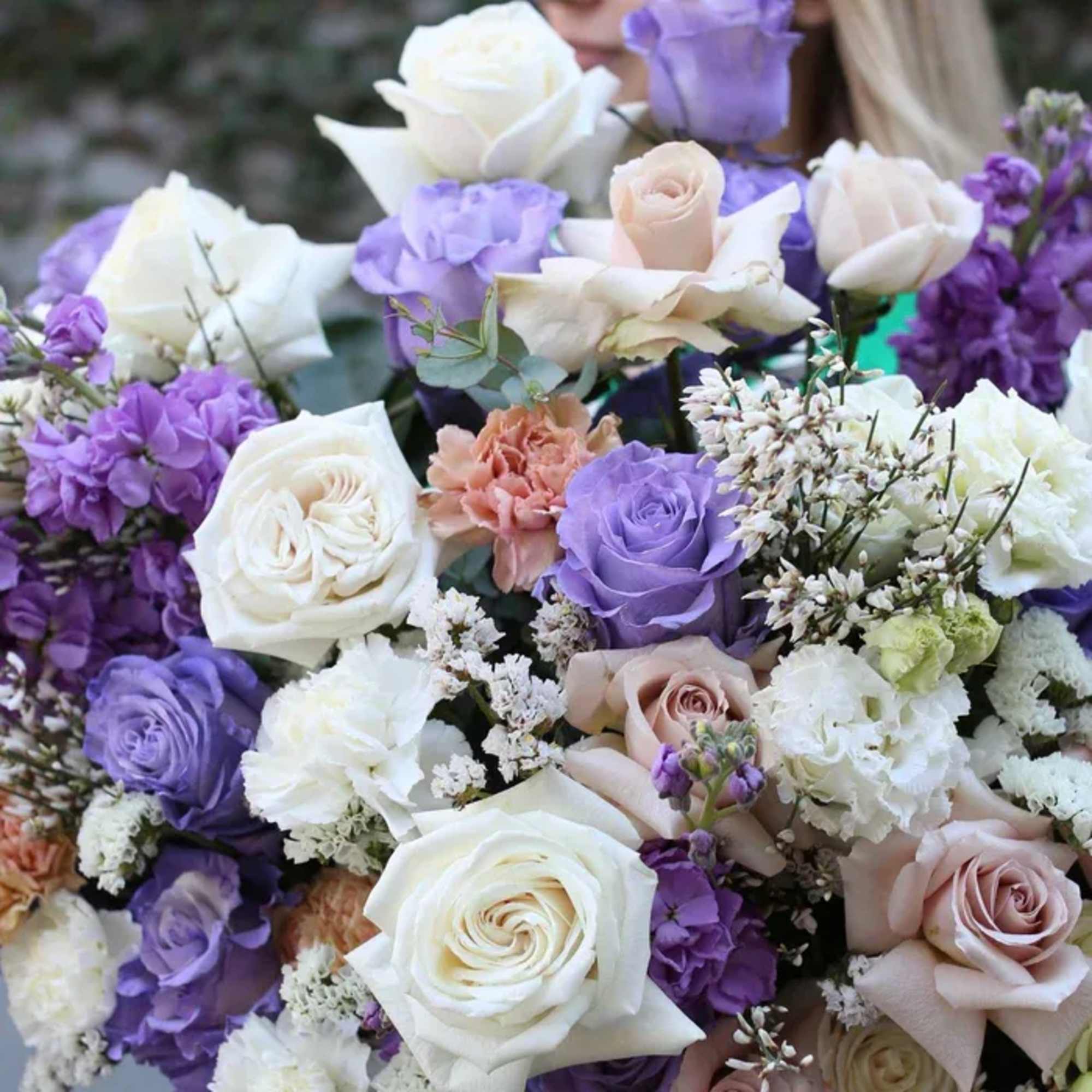 Bouquet of white, lavender, and blush roses with purple blooms