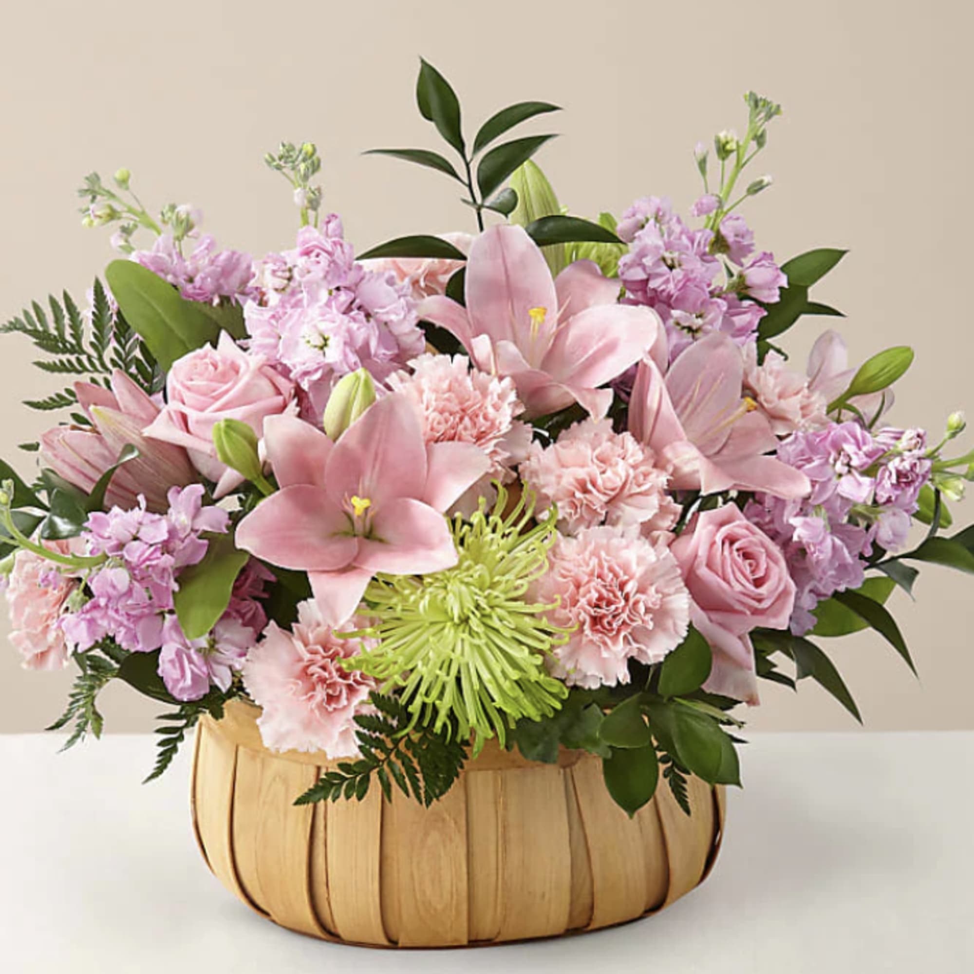 Pink floral arrangement in a woven basket with lilies and roses
