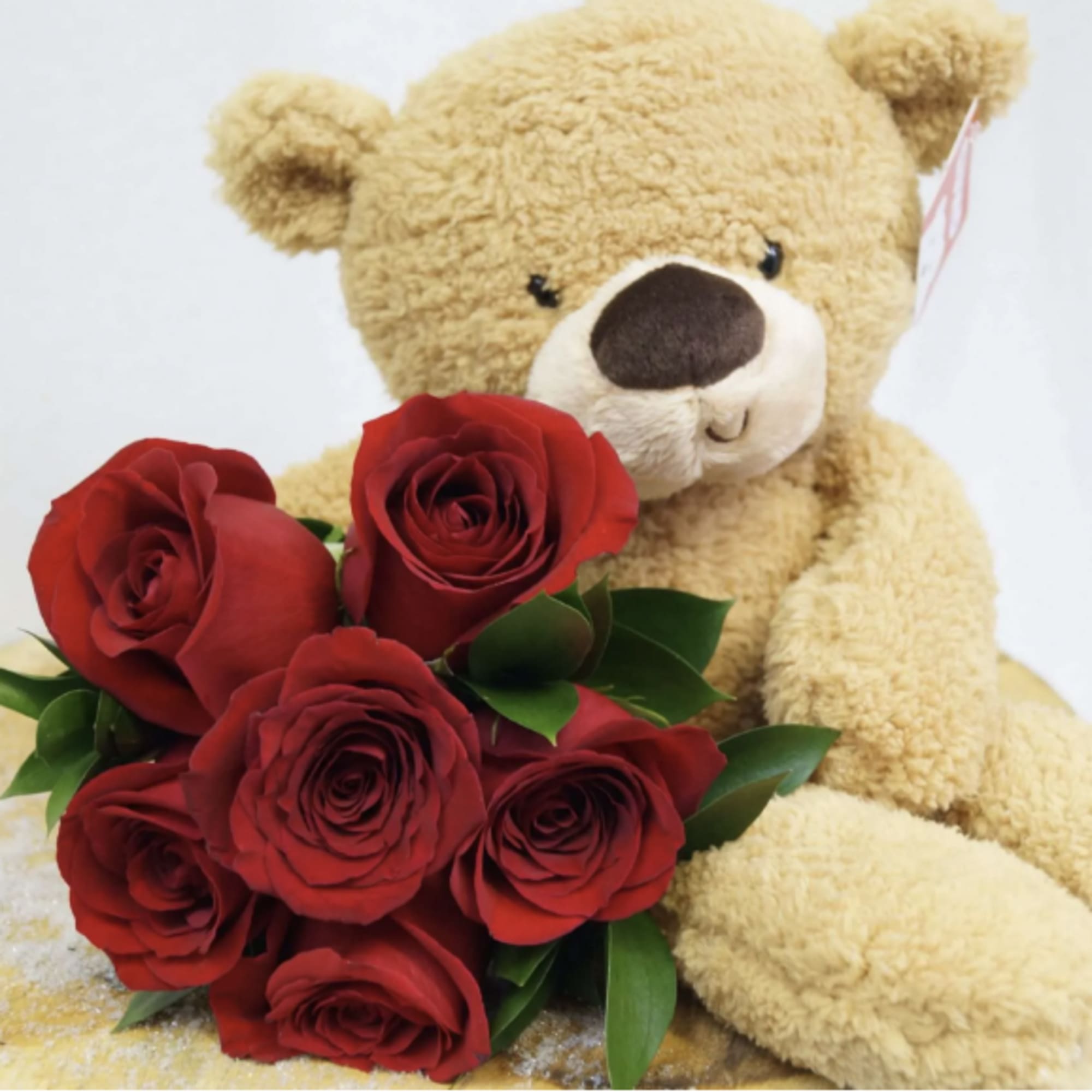 Teddy bear holding a bouquet of red roses