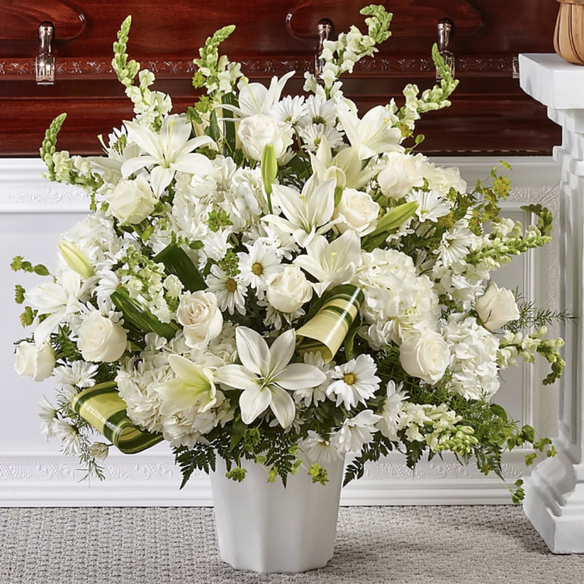 White floral arrangement in a white vase with lilies and roses