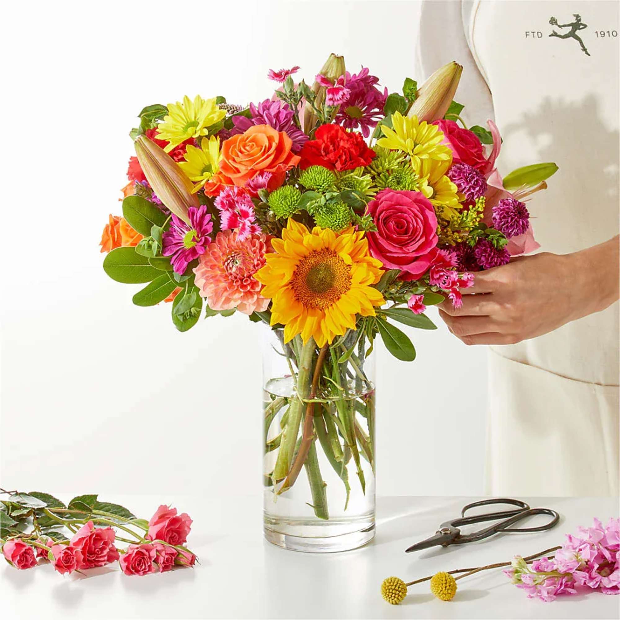 Colorful mixed bouquet in a clear glass vase with roses and sunflowers