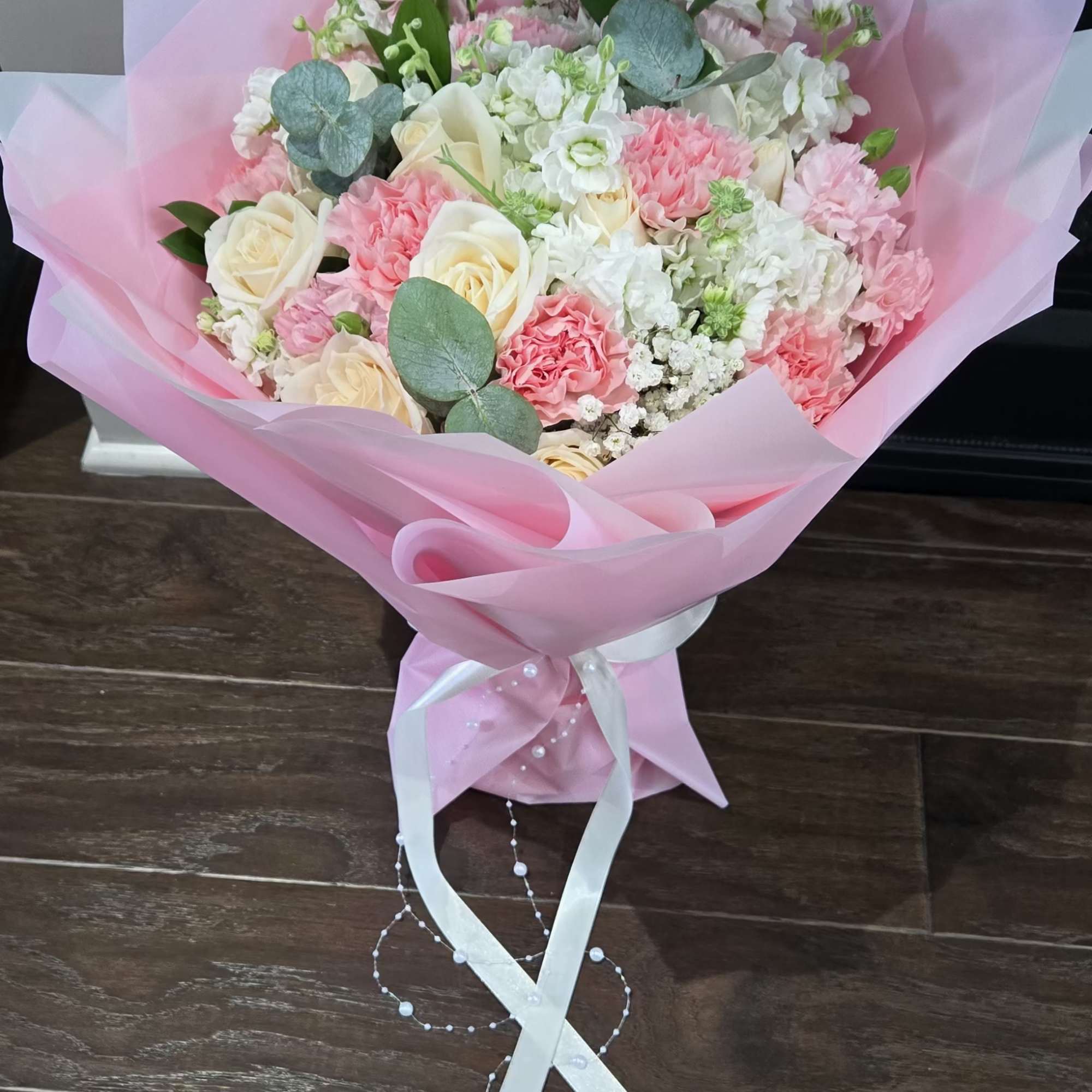 Pink and white bouquet with roses and carnations wrapped in pastel paper