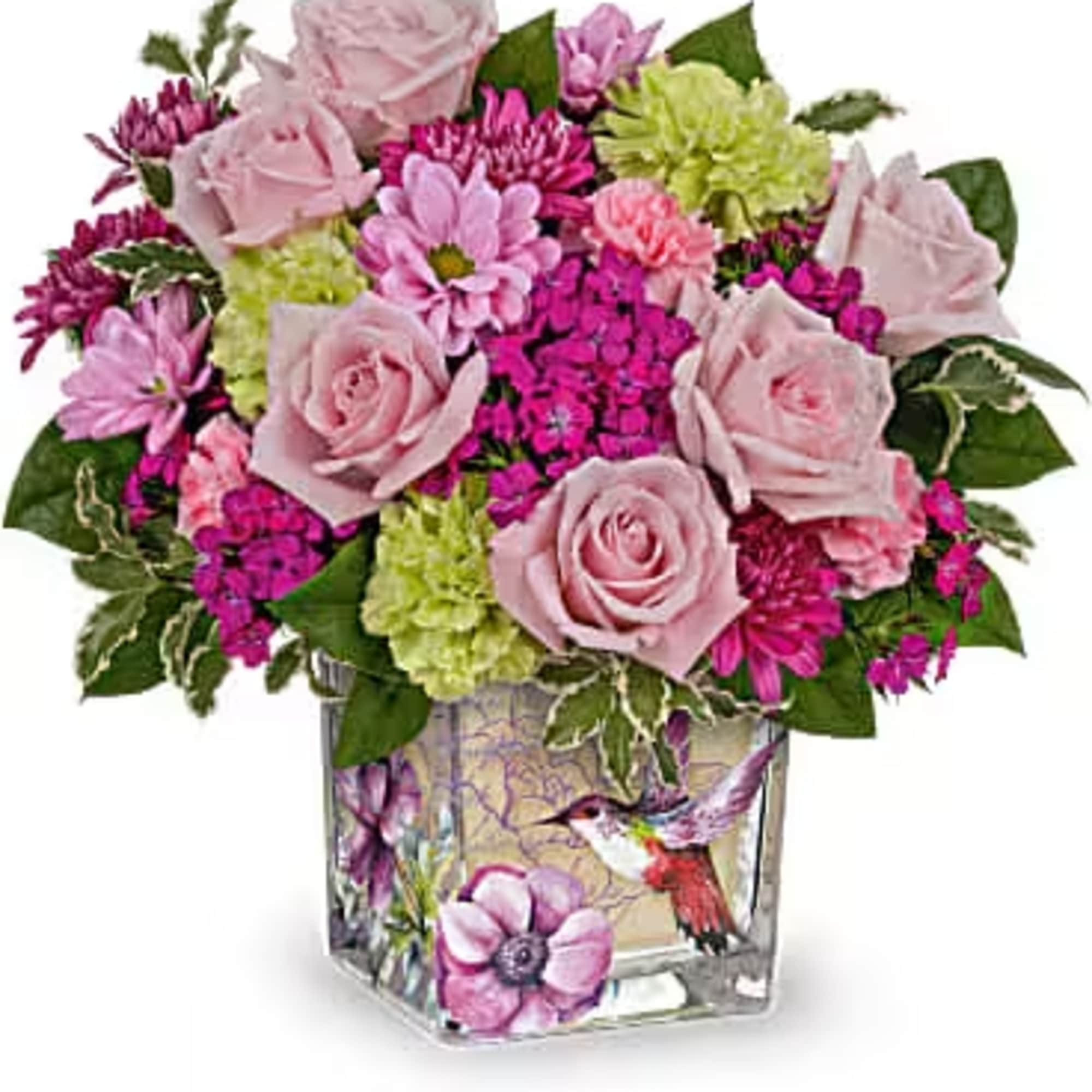 Pink roses and mixed blooms in a square glass vase with a hummingbird design
