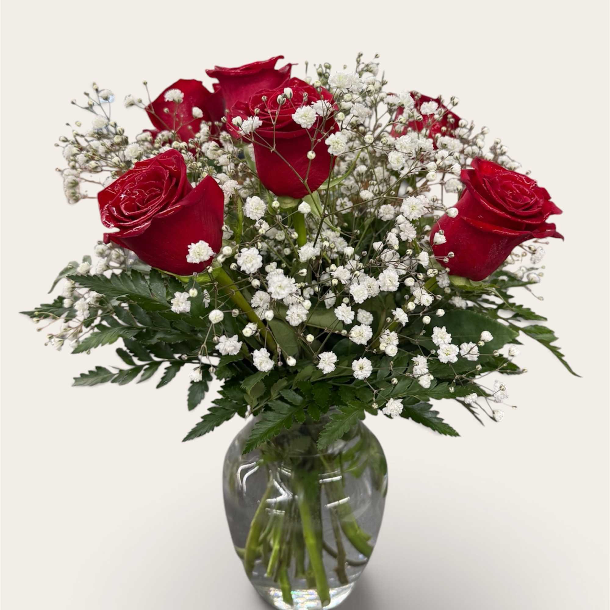 Red roses and baby's breath in a clear glass vase