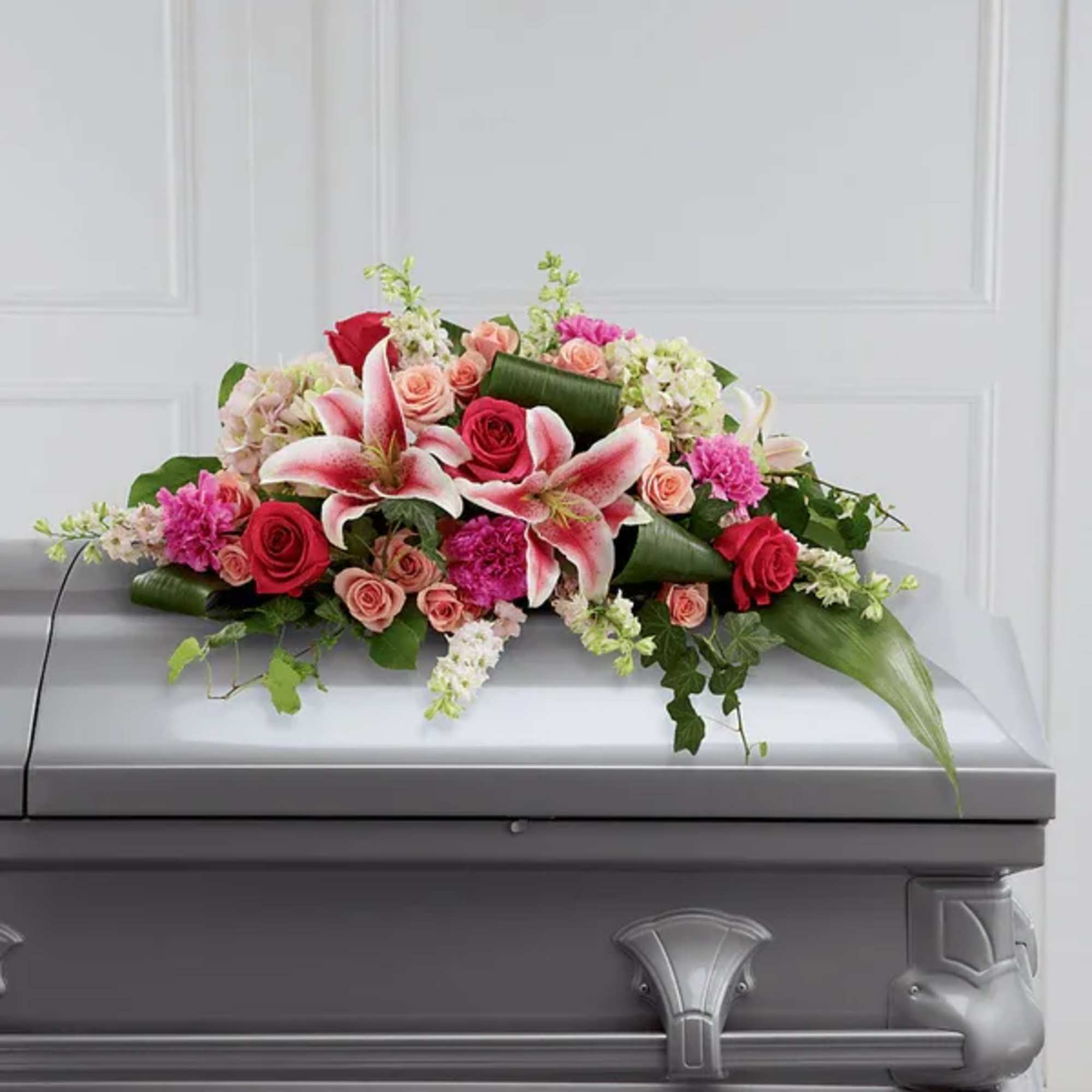 Floral casket spray with pink lilies and red roses