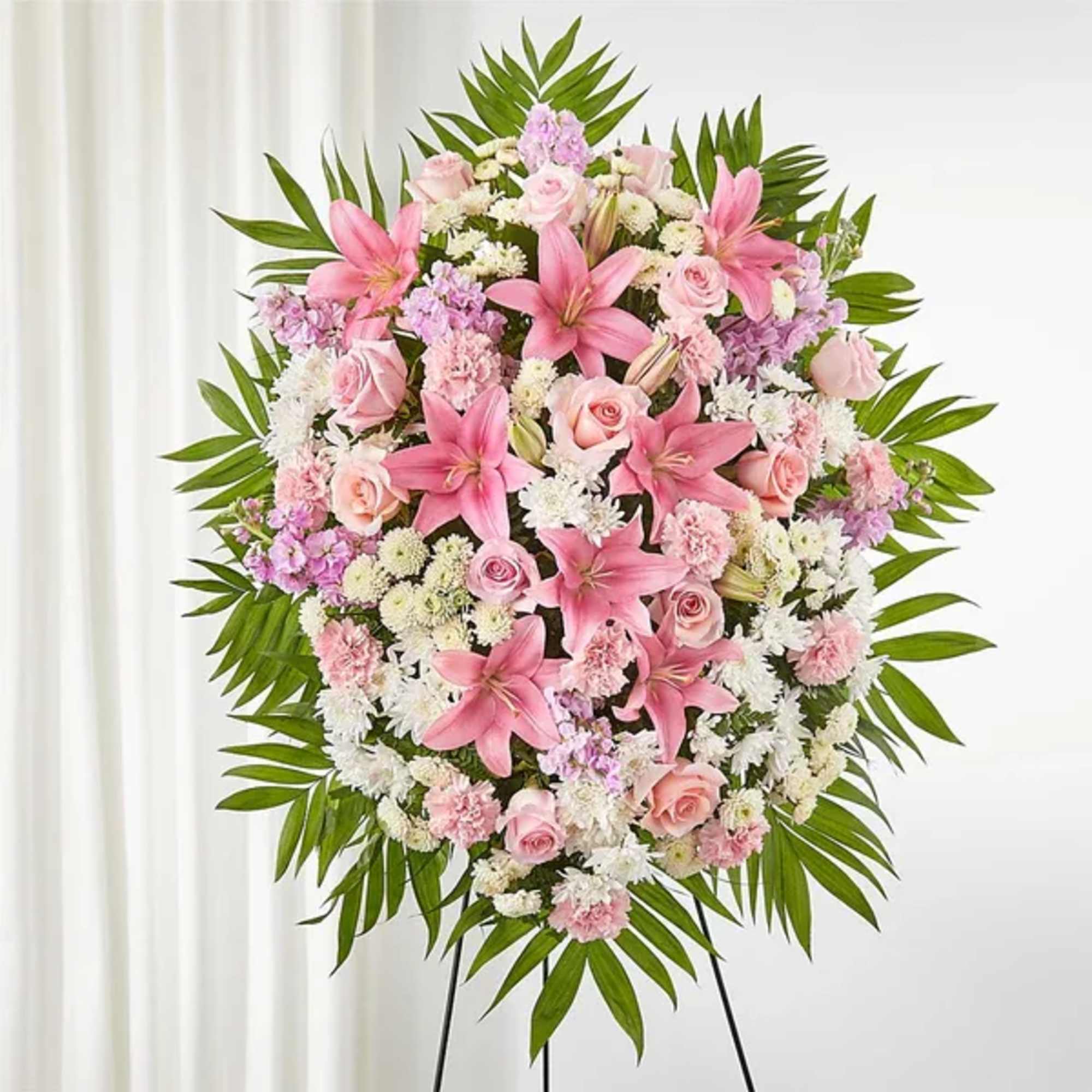 Heart-shaped floral spray with pink lilies and roses on a stand