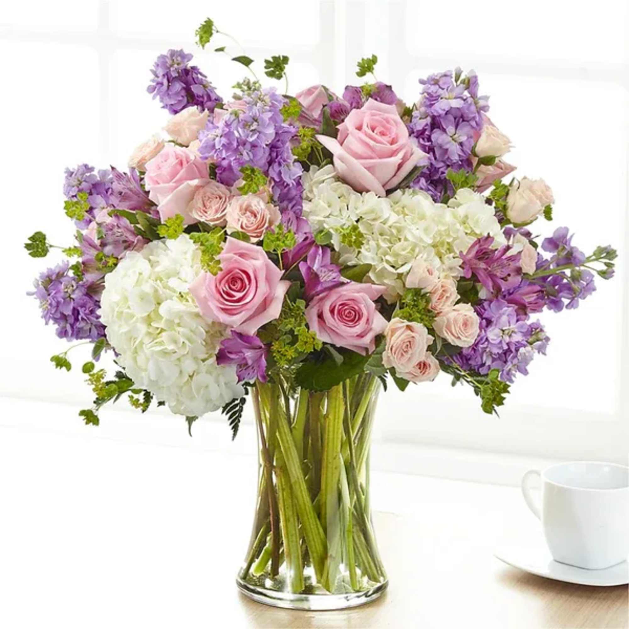 Pink roses and purple flowers in a clear glass vase