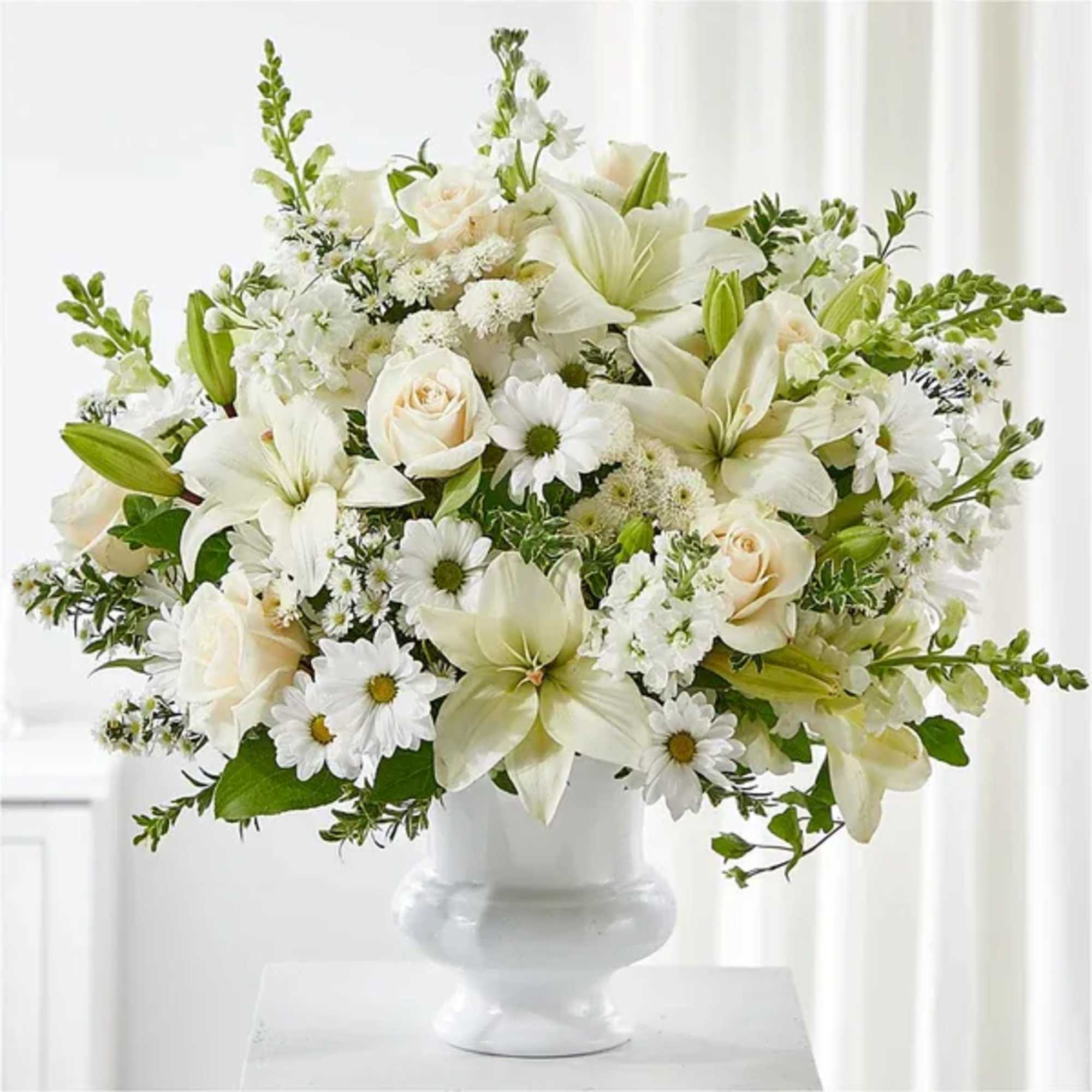 White floral arrangement with lilies, roses, and daisies in a white vase