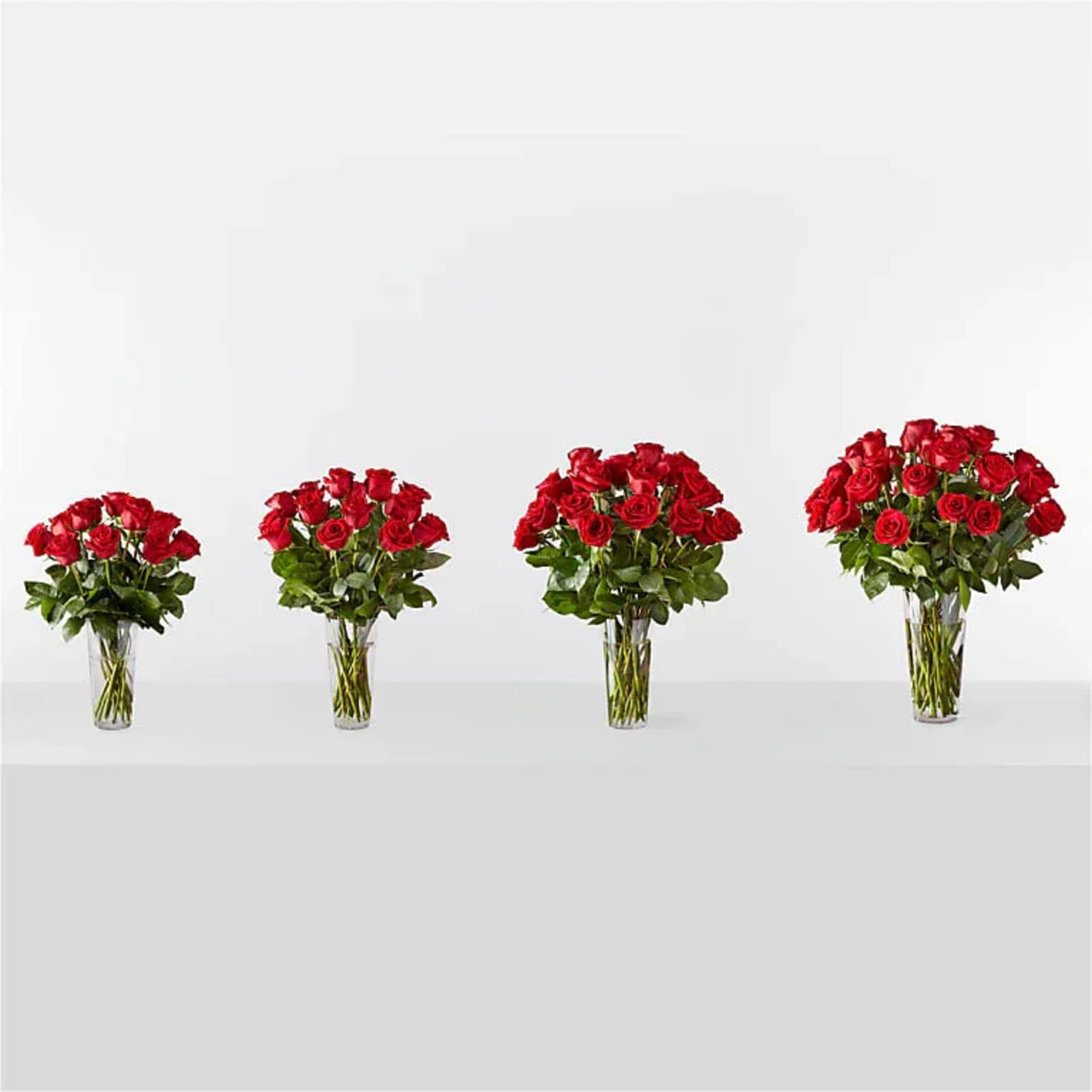 Four red rose bouquets in clear glass vases