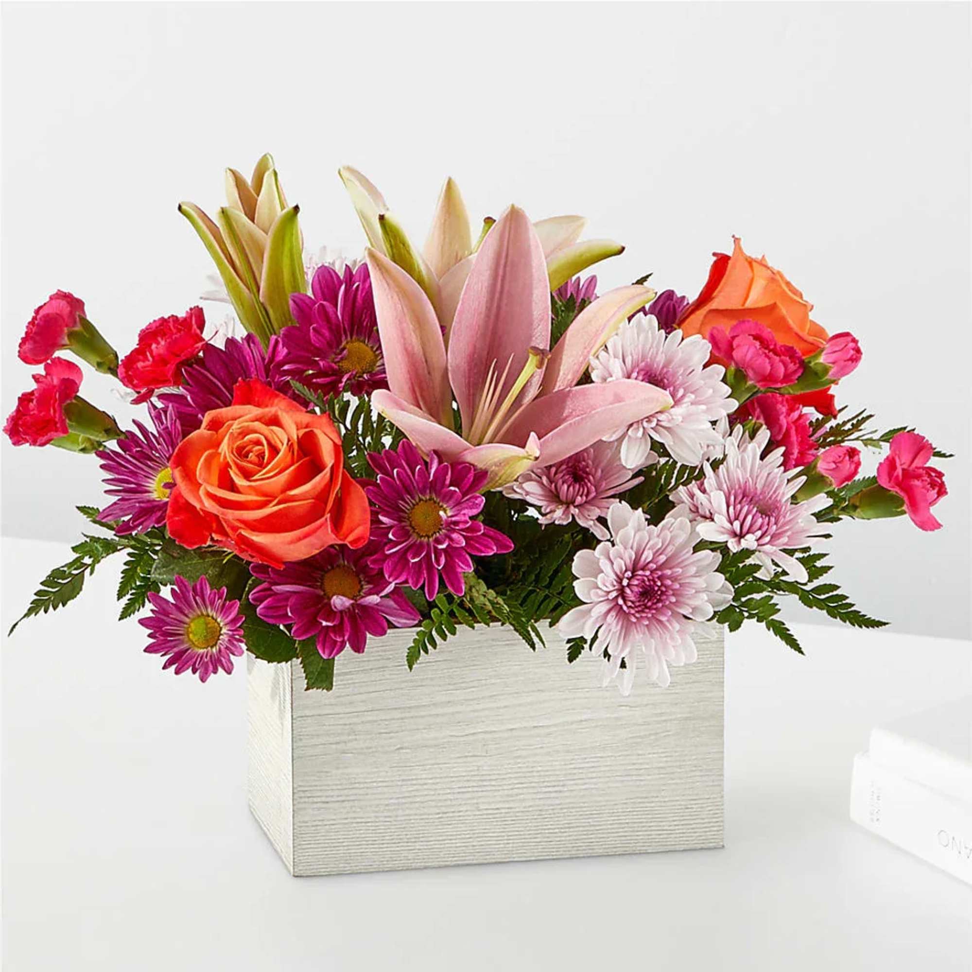 Mixed bouquet of roses, lilies, and daisies in a square box