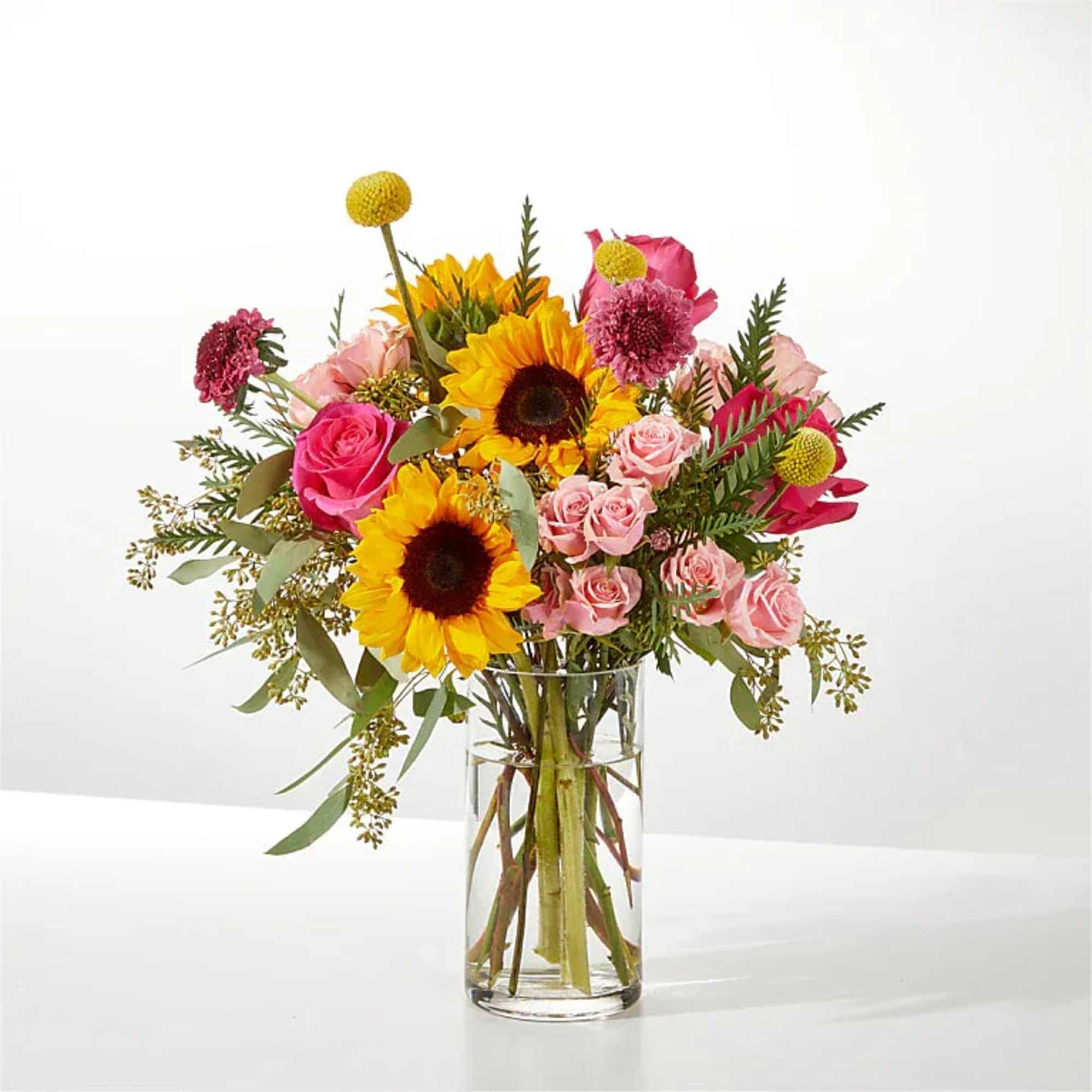 Bouquet of sunflowers and pink roses in a clear glass vase