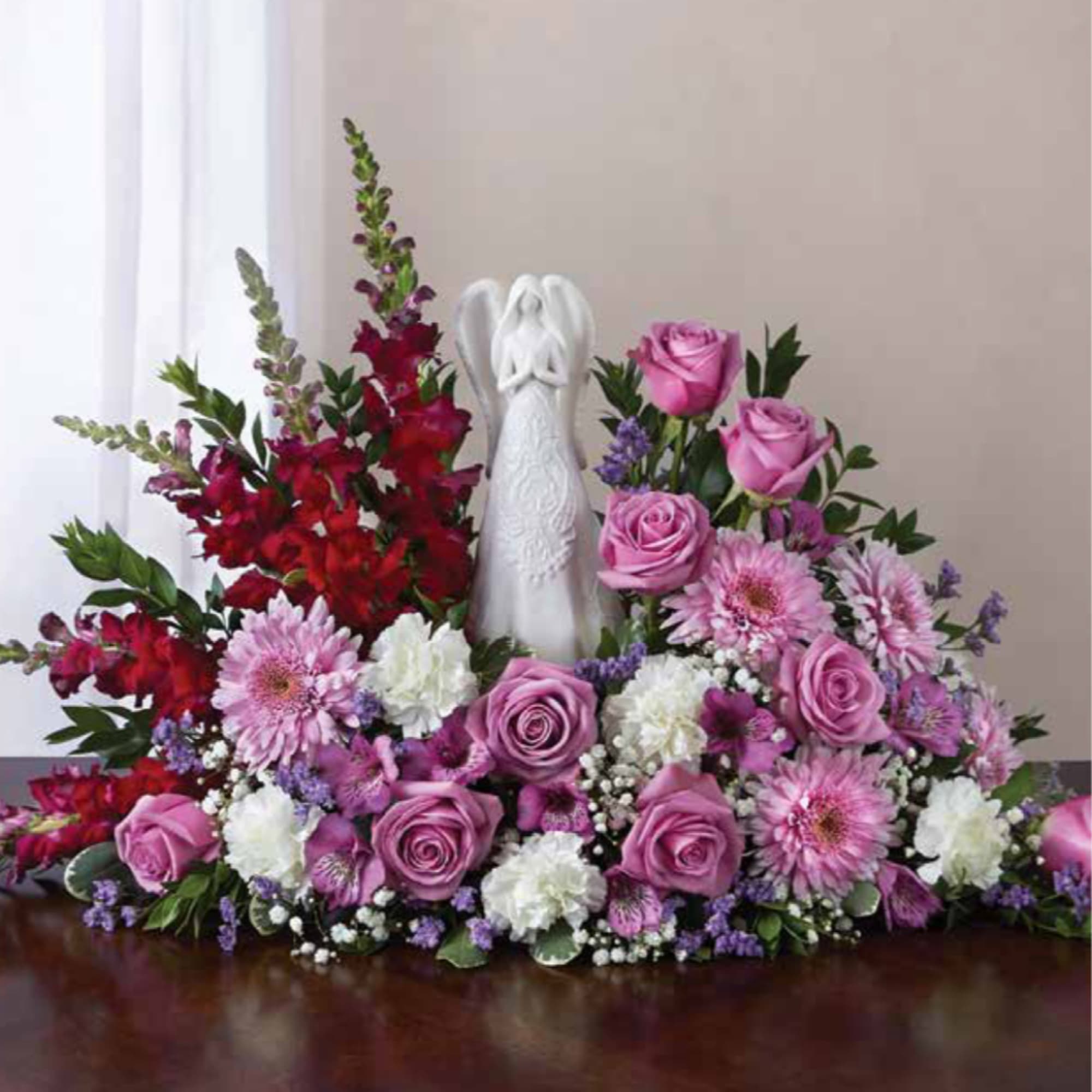 Pink and red floral arrangement with a white angel figurine in the center, photo 2 of 2