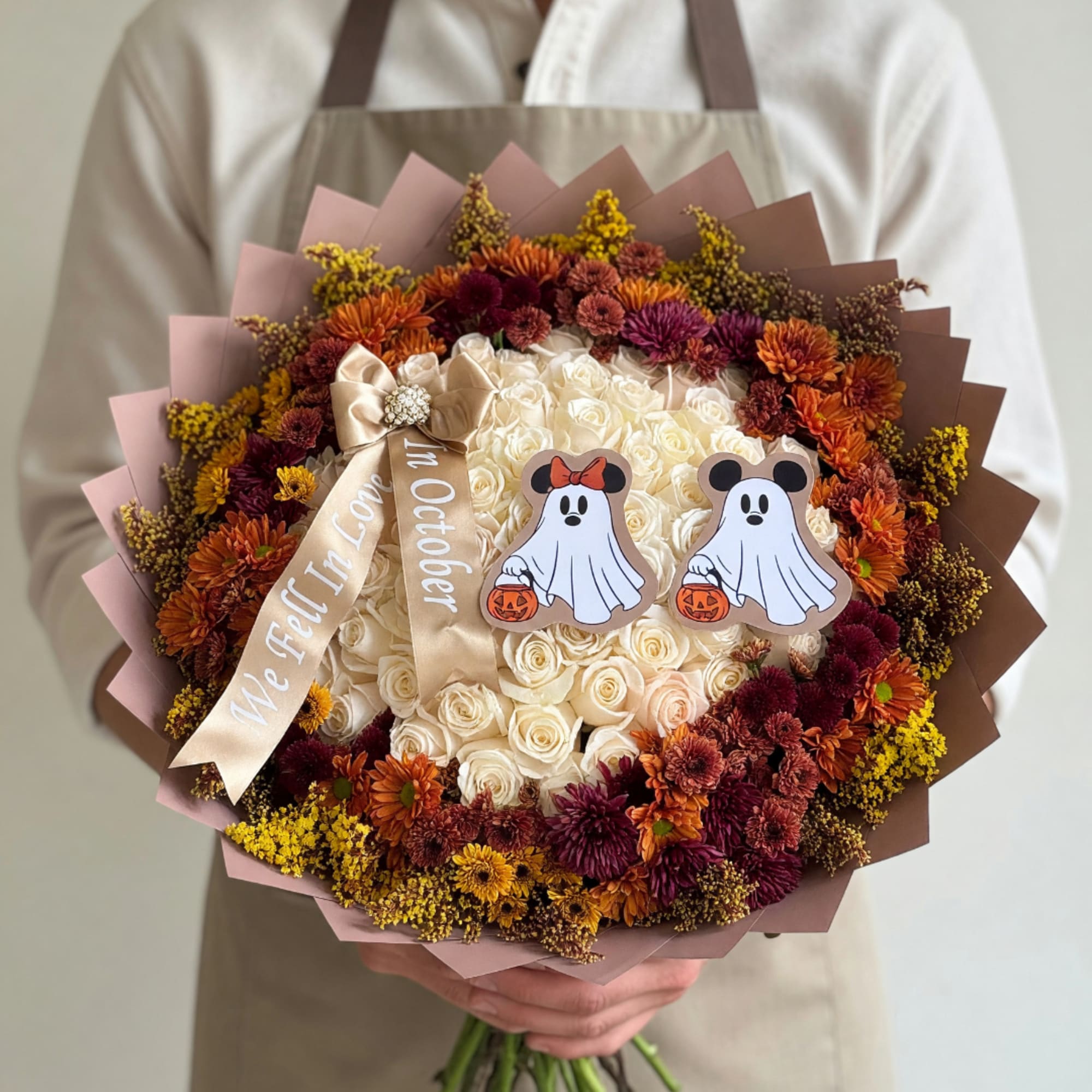 Bouquet of cream and autumn-toned flowers with Halloween ghost decorations