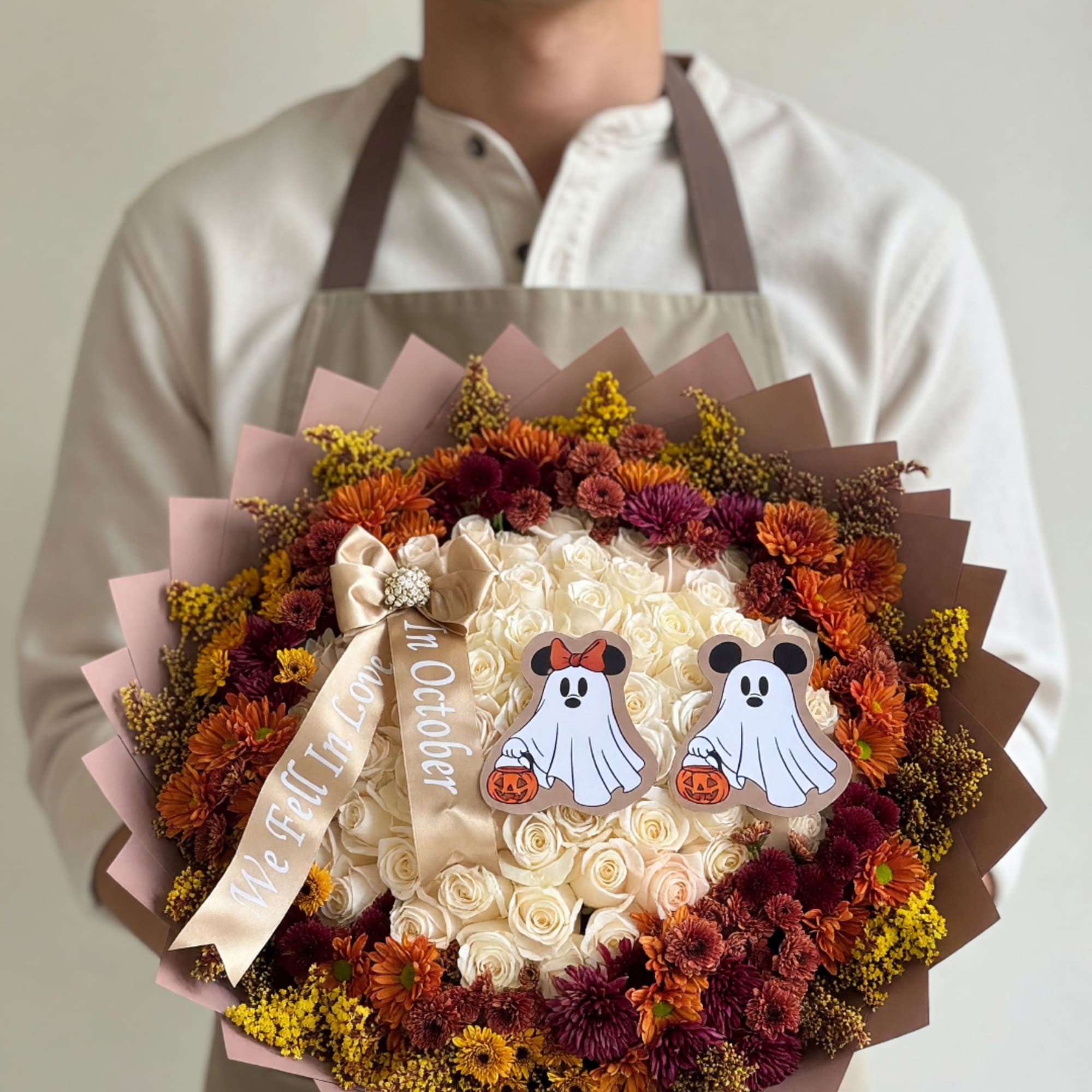 Large bouquet of white roses with orange and burgundy flowers, decorated with Halloween ghost cutouts